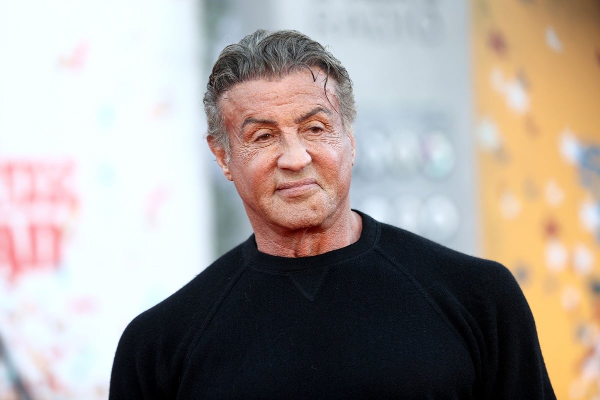 Sylvester Stallone smirking while wearing a black shirt.
