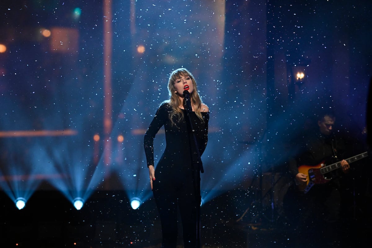 Taylor Swift sings on stage as snow falls around her.