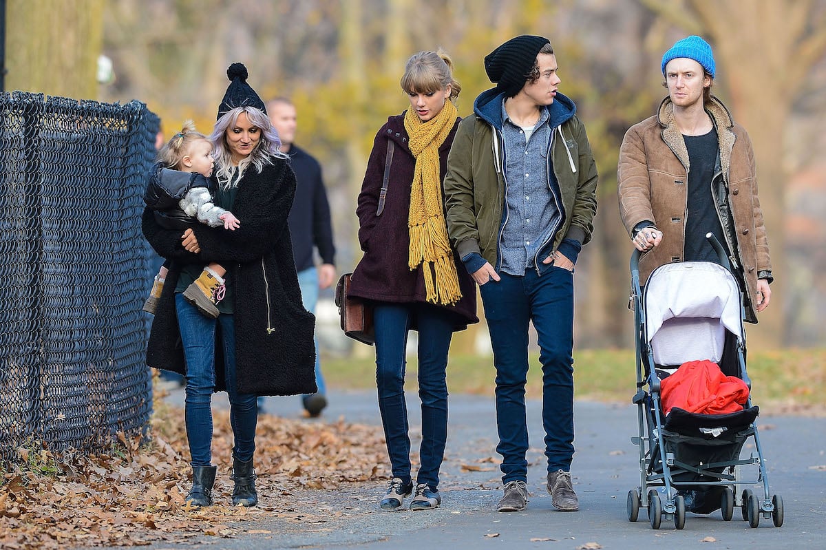 Taylor Swift and Harry Styles walk together in a park.