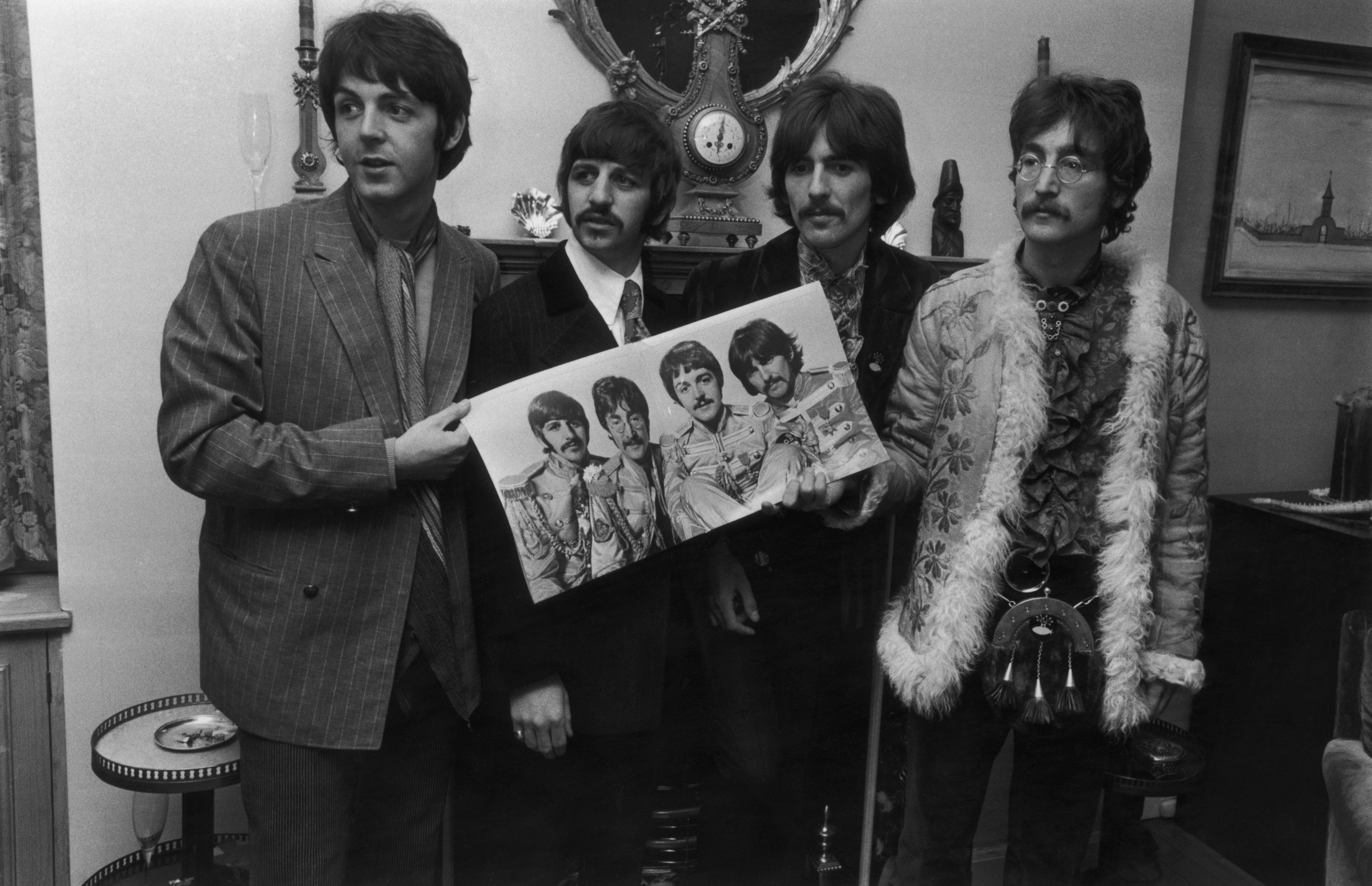 The Beatles hold a photo of themselves.