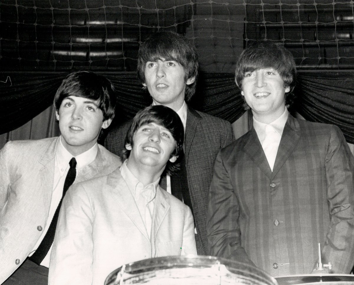 The Beatles band members pose together, smiling.
