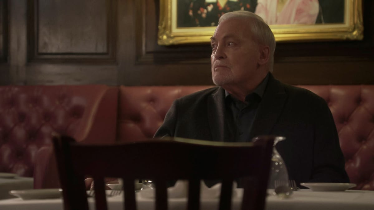 Stacy Keach as Vesco in The Blacklist Season 9. Vesco sits in a booth looking off to the side.