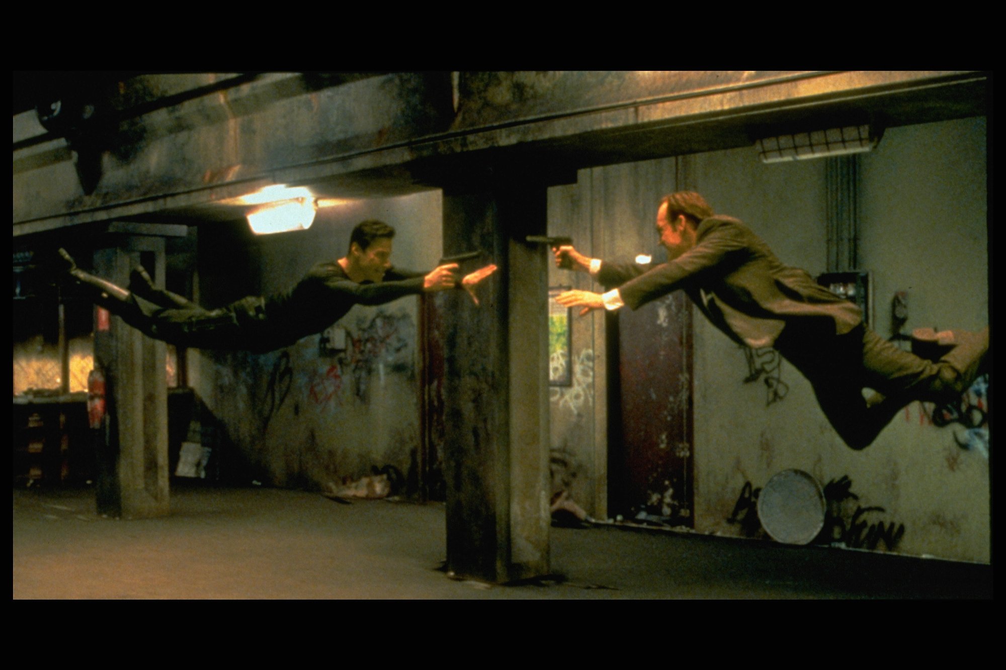 'The Matrix' stars Keanu Reeves as Neo and Hugo Weaving as Agent Smith facing each other mid-air with guns