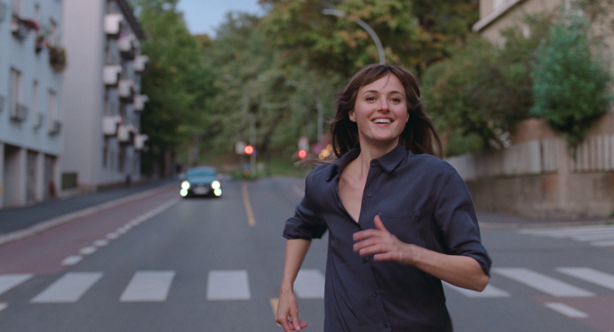 'The Worst Person in the World' review star Renate Reinsve as Julie running down the street with a car in the distance behind her
