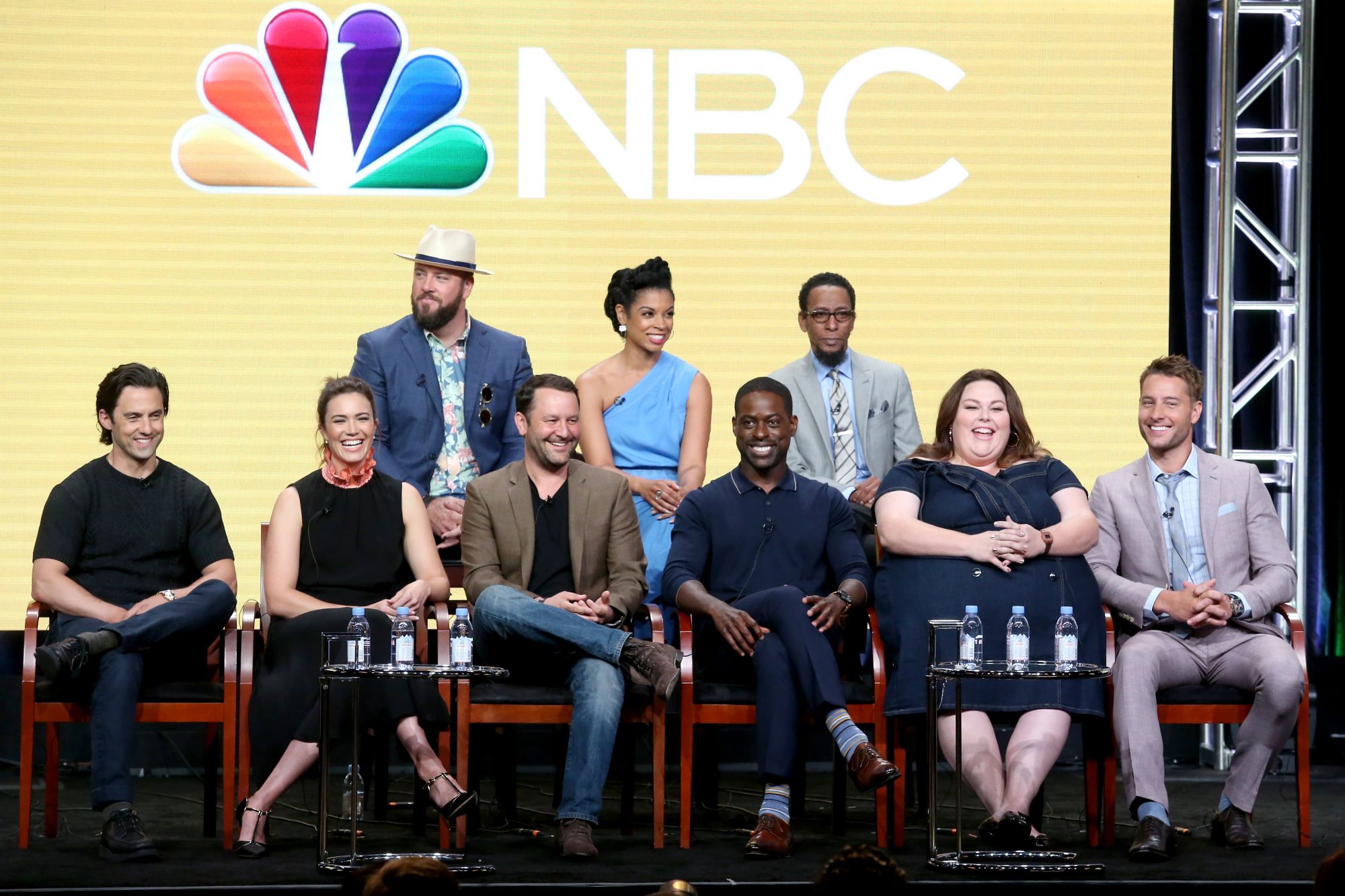 'This Is Us' cast and crew Milo Ventimiglia, Mandy Moore, Chris Sullivan, Dan Fogelman, Susan Kelechi Watson, Sterling K. Brown, Ron Cephas Jones, Chrissy Metz, and Justin Hartley sit onstage in front of a screen that has the NBC logo on it. Sullivan, Kelechi Watson, and Cephas Jones sit in the back row. Ventimiglia, Moore, Fogelman, Brown, Metz, and Hartley sit in the front row.
