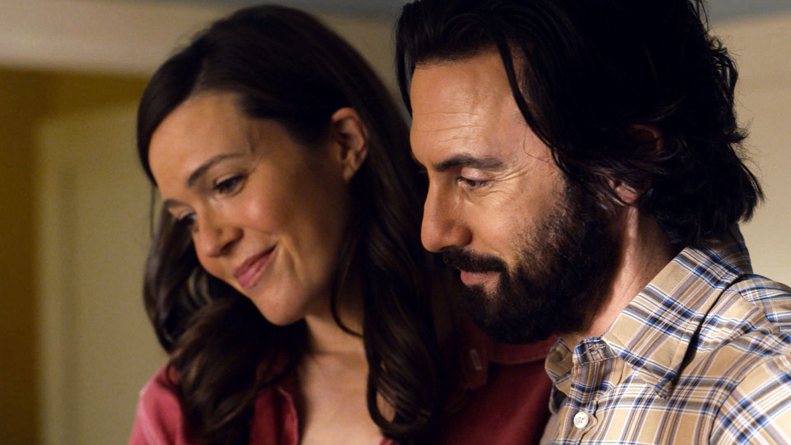 'This Is Us' Season 6 stars Mandy Moore and Milo Ventimiglia, who will appear in the trailer, are in character as Rebecca and Jack Pearson. Moore wears a pink shirt. Ventimiglia wears a light brown and blue plaid shirt.