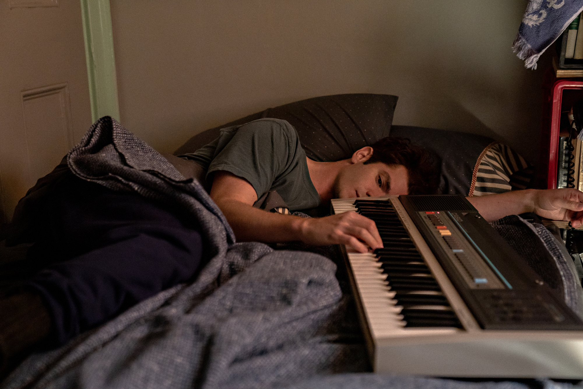'Tick, Tick Boom' star Andrew Garfield as Jonathan Larson with musical keyboard laying in bed