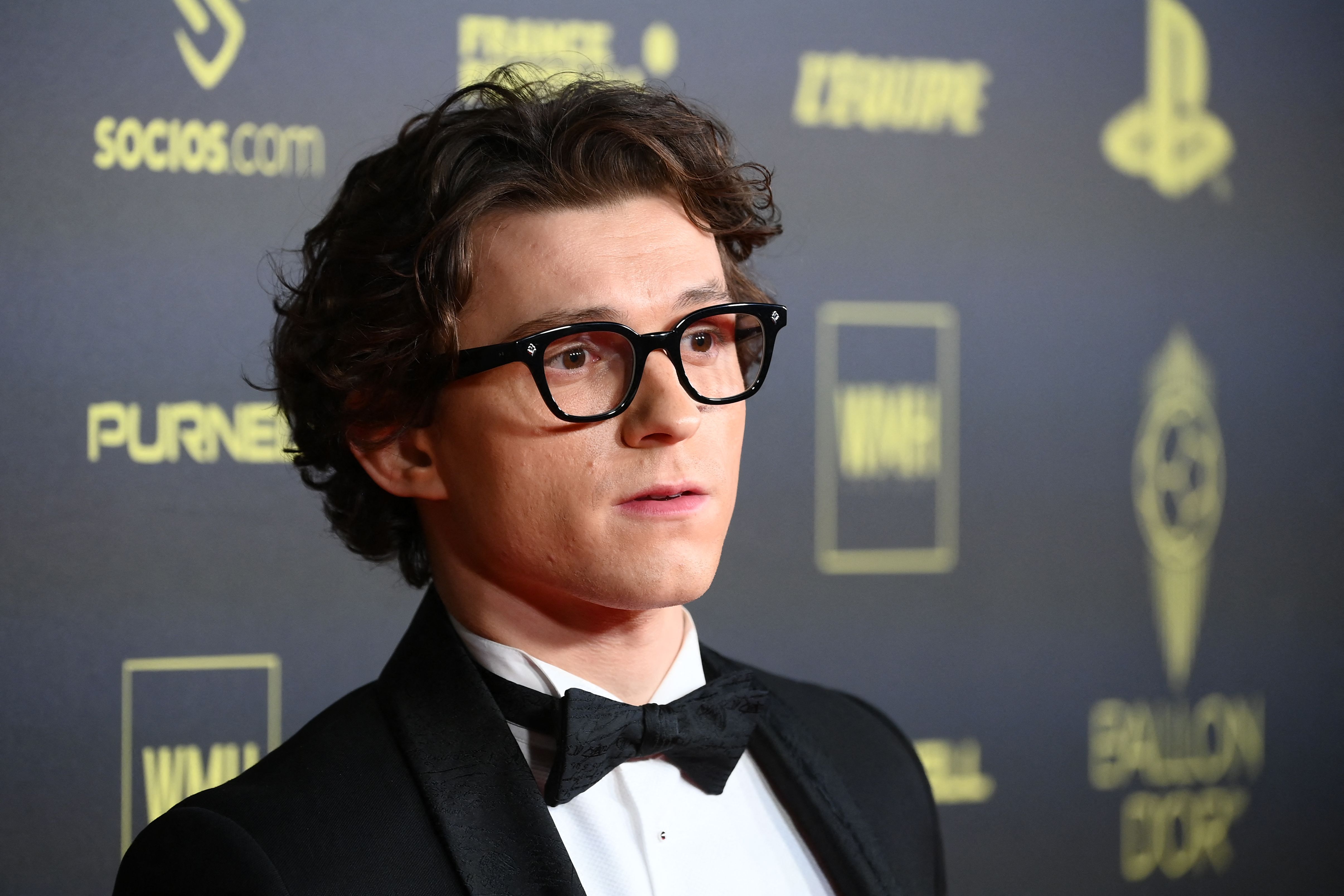 'Spider-Man' actor Tom Holland wears a black and white tux and a pair of black glasses.