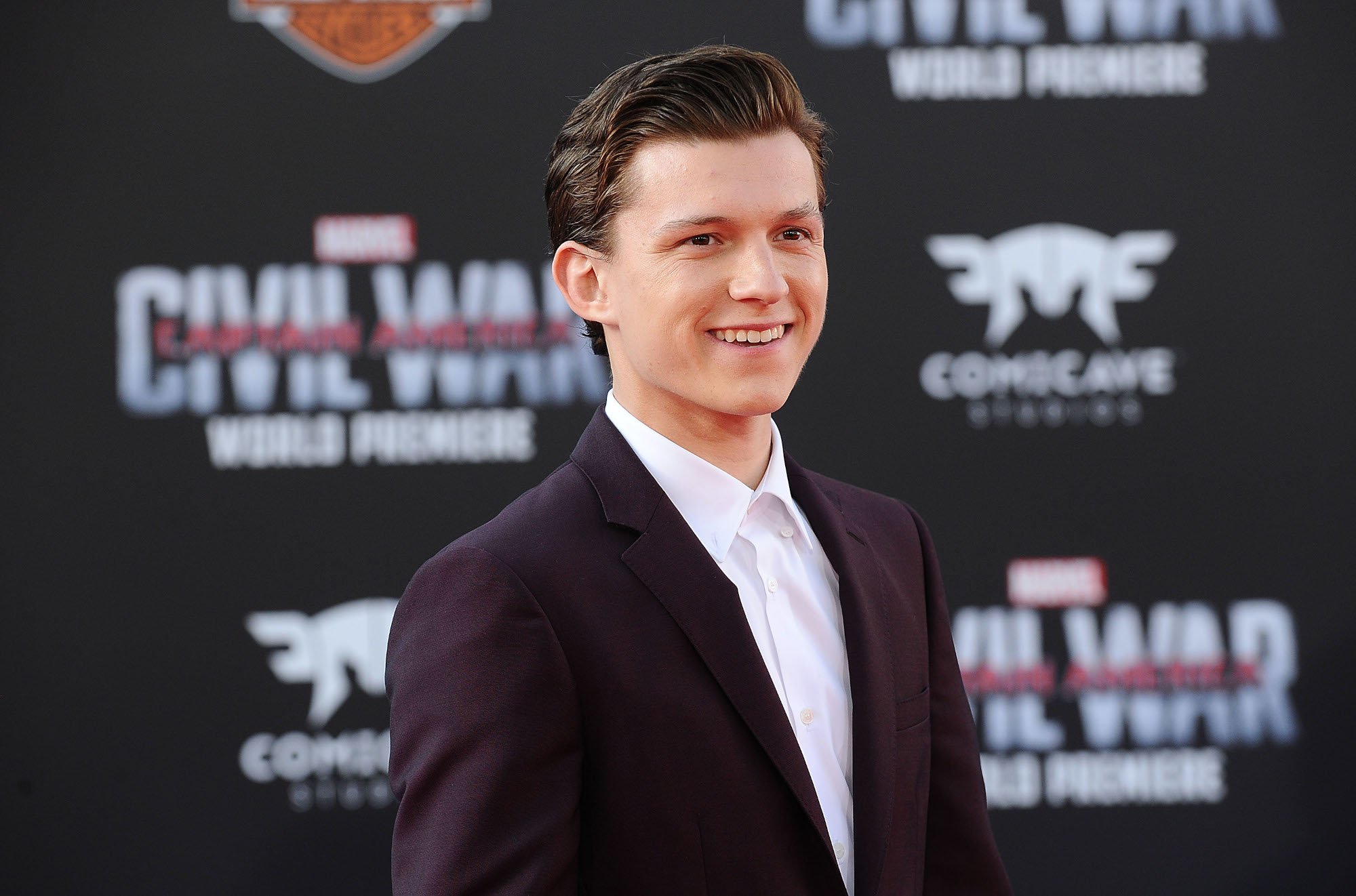 Spider-Man actor Tom Holland wearing a black suit and white shirt at the premiere for 'Captain America: Civil War.' Will Tom Holland's Peter Parker continue appearing in the MCU?