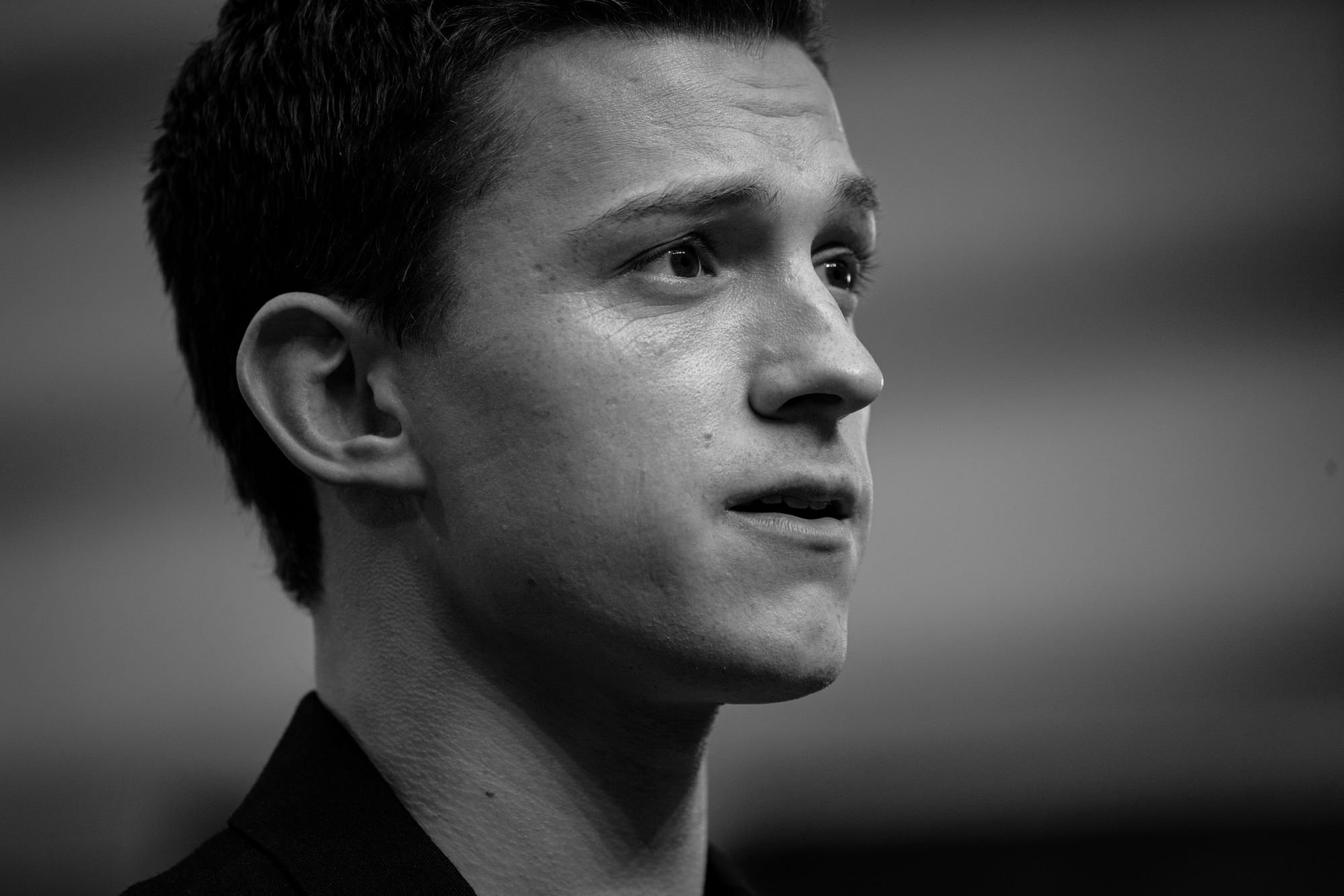 'Spider-Man: No Way Home' star Tom Holland wears a black suit. The photo has been converted to black and white.