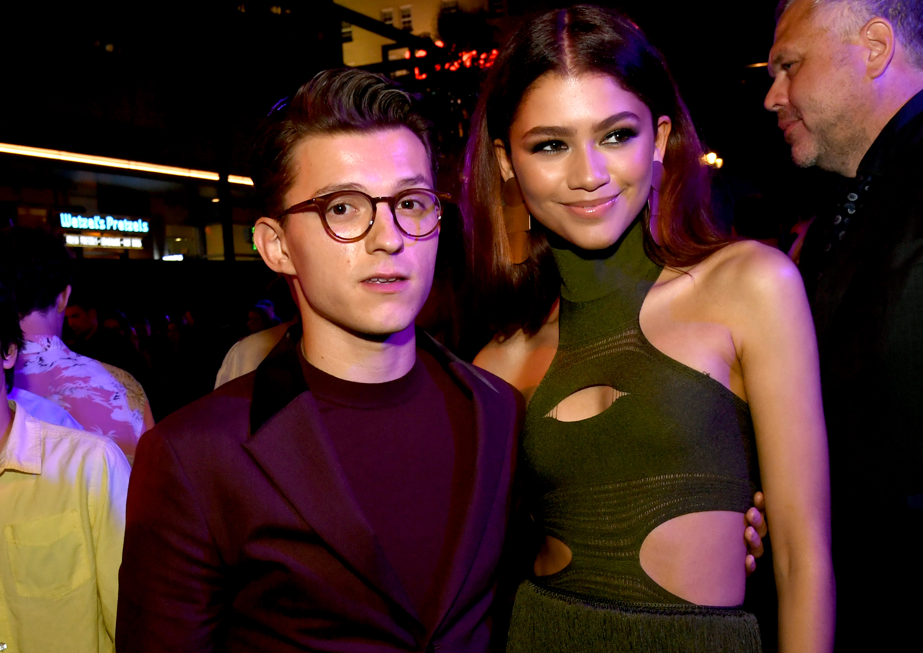 Tom Holland and Zendaya. He's wearing a brown suit and has his arm around her. She's wearing a green dress.
