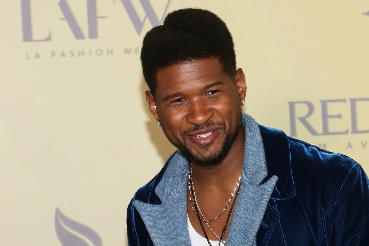 Usher smiling in front of a yellow background