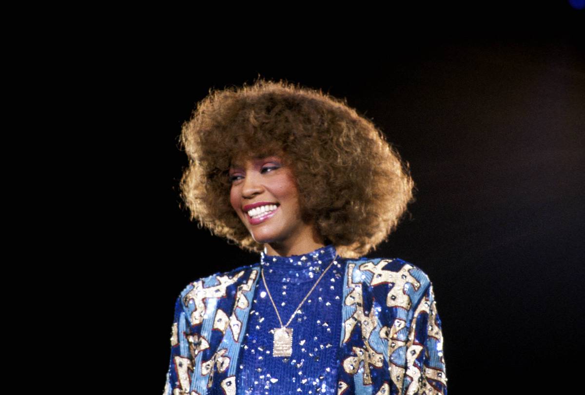 Whitney Houston smiling in front of a black background