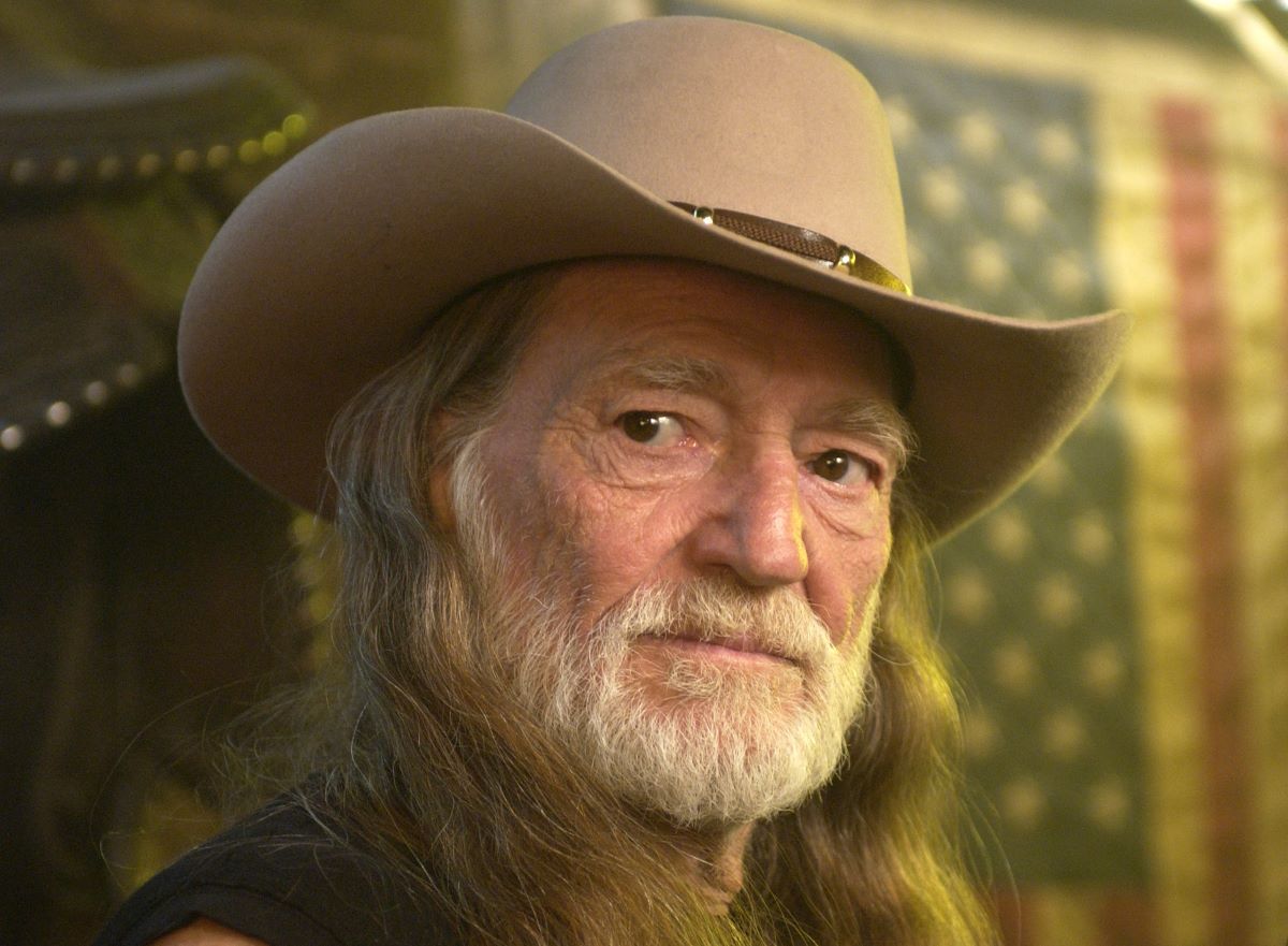 Willie Nelson looks to the side, hair down and wearing a cowboy hat