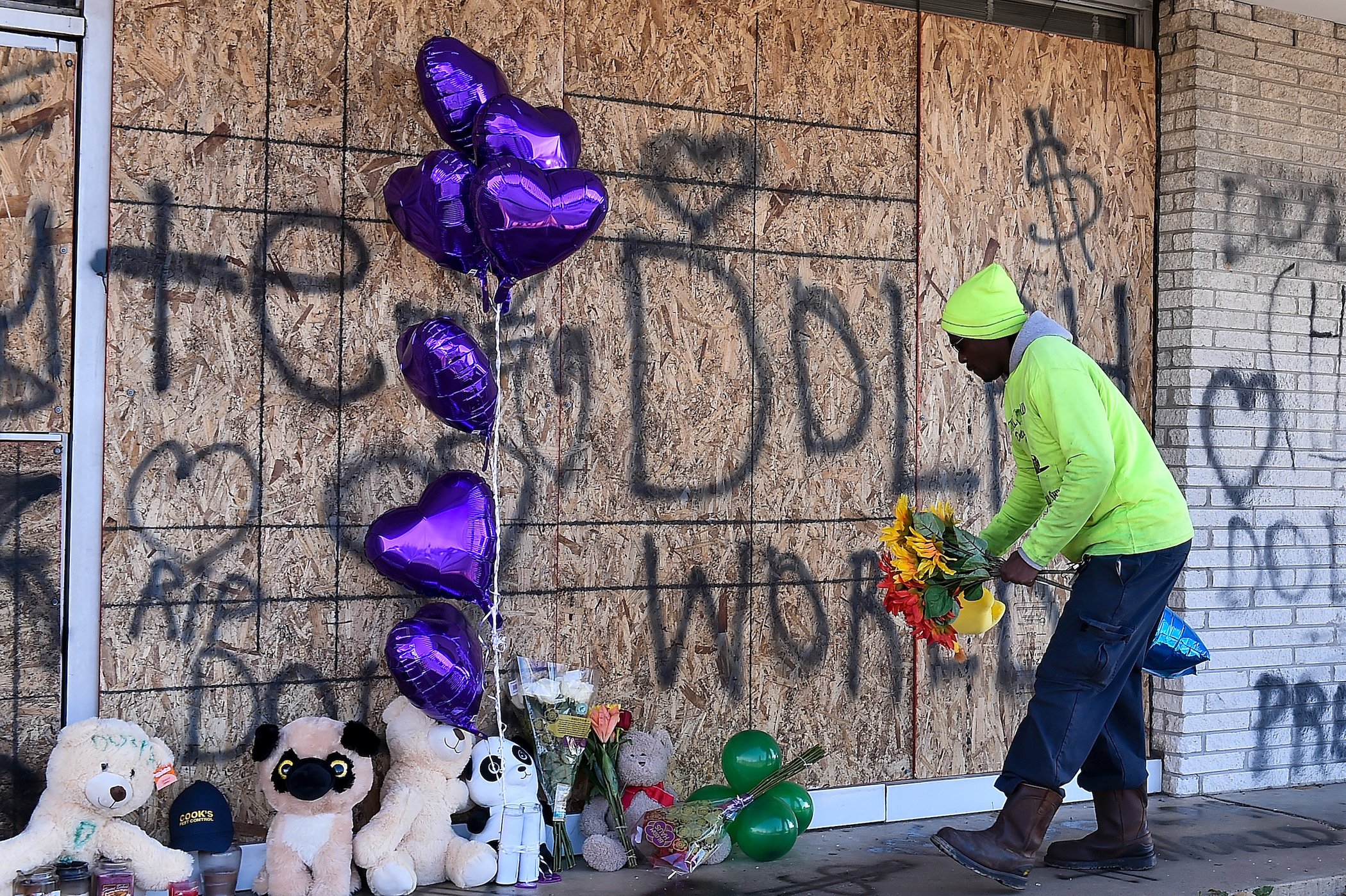 A man putting flowers down at Young Dolph's memorial