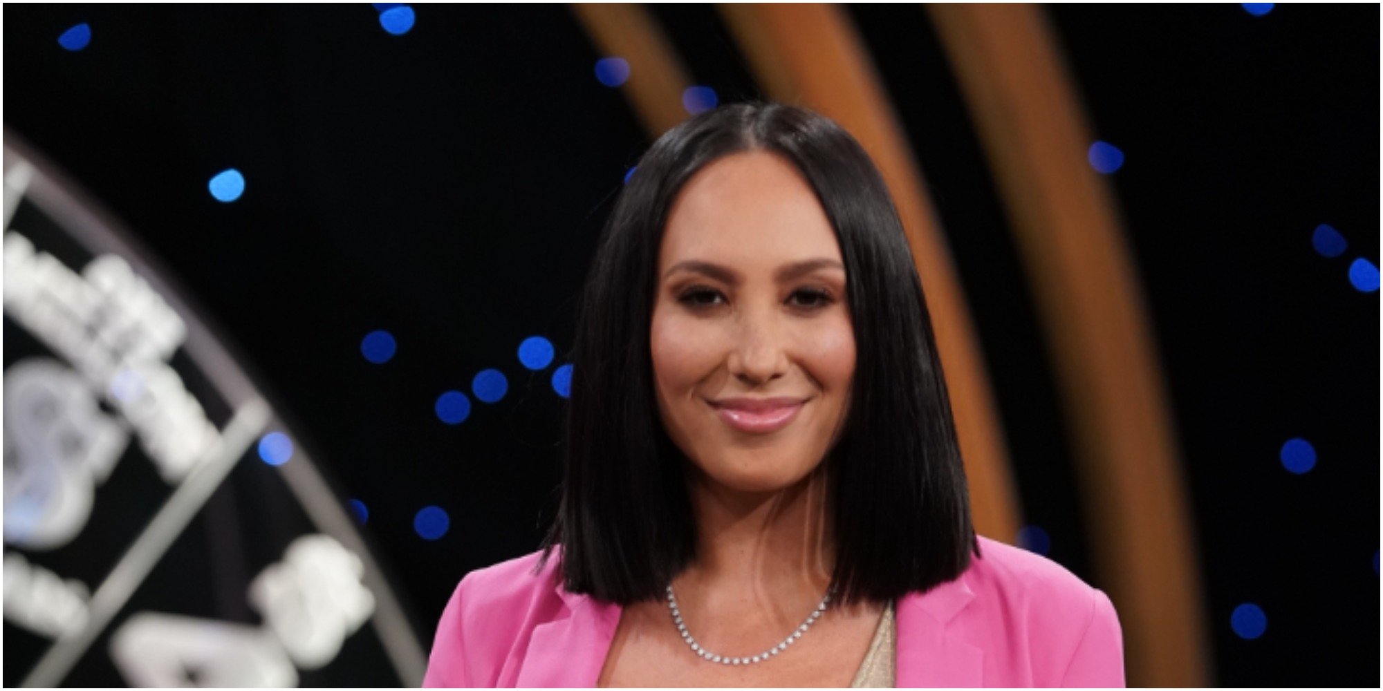 "Dancing with the Stars" pro Cheryl Burke wears a pink jacket and smiles for the camera.