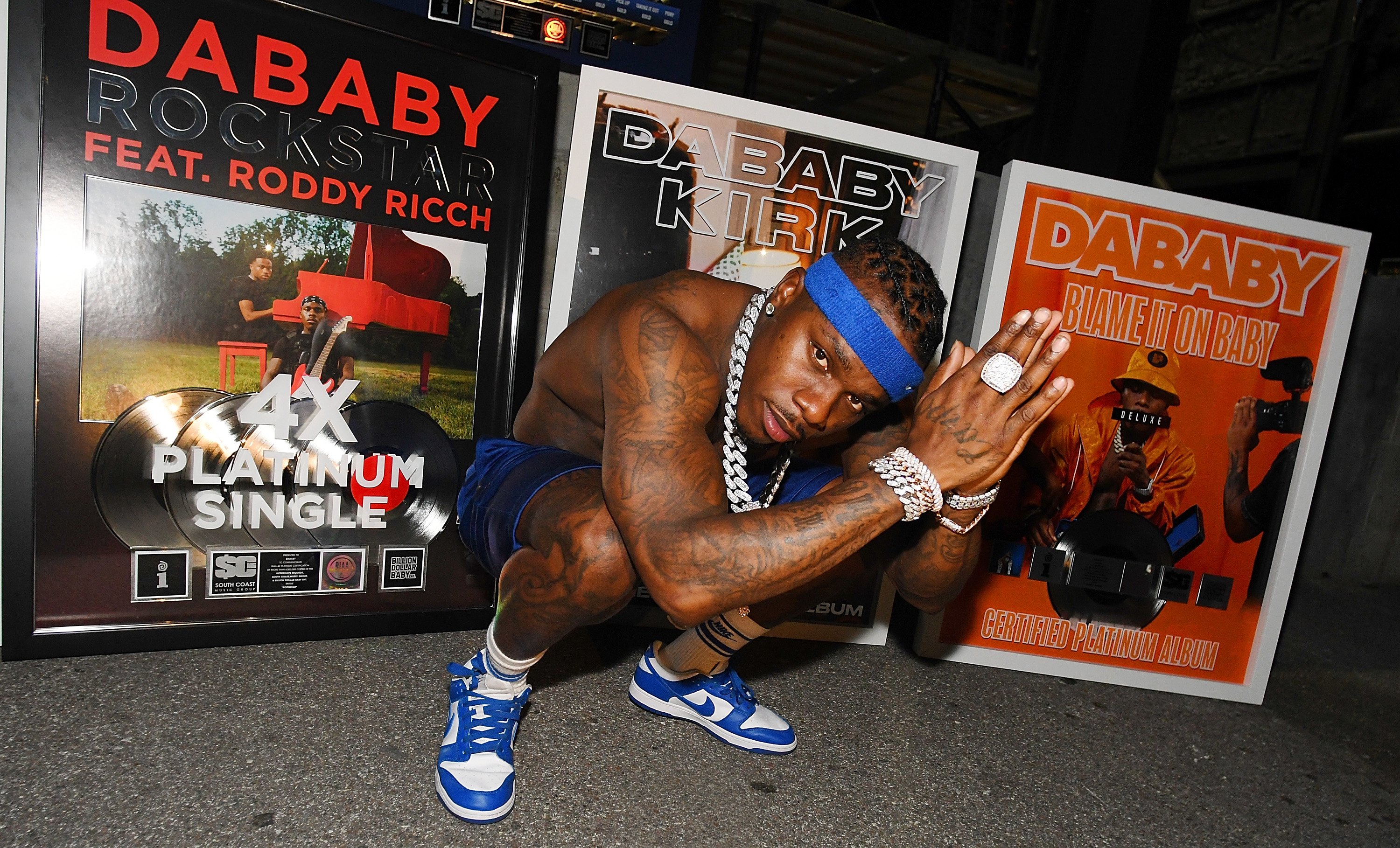 DaBaby squatting while shirtless