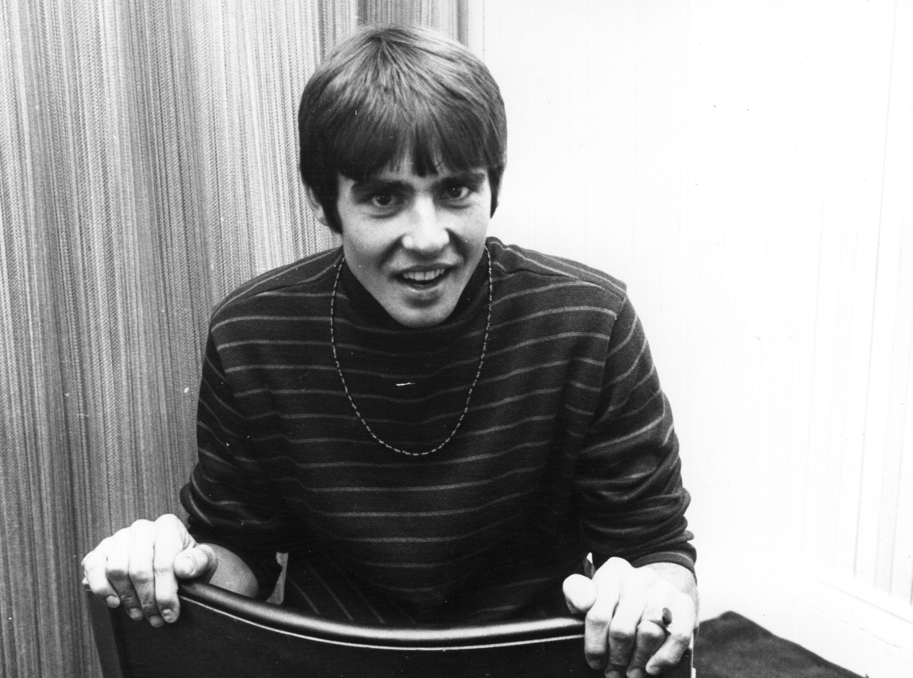 The Monkees' Davy Jones in front of a curtain