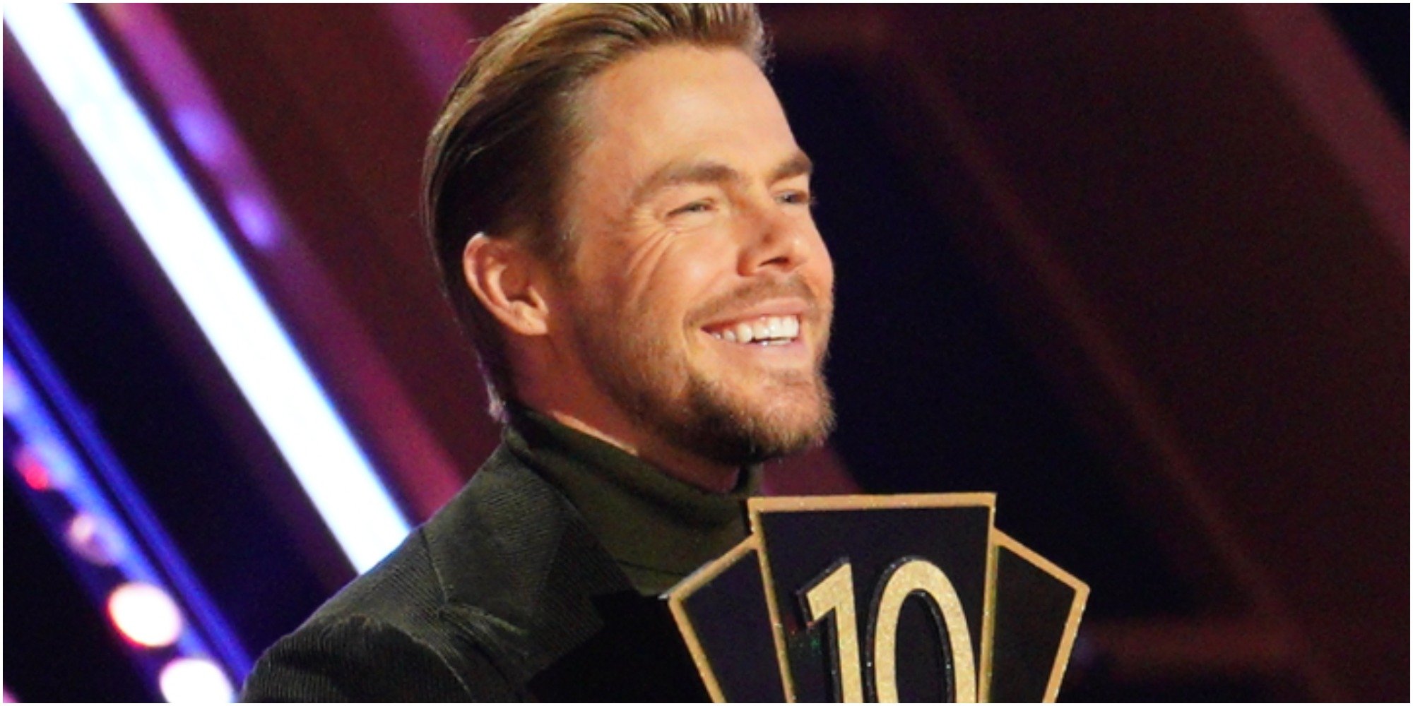 Derek Hough holds a 10 paddle on the set of DWTS.