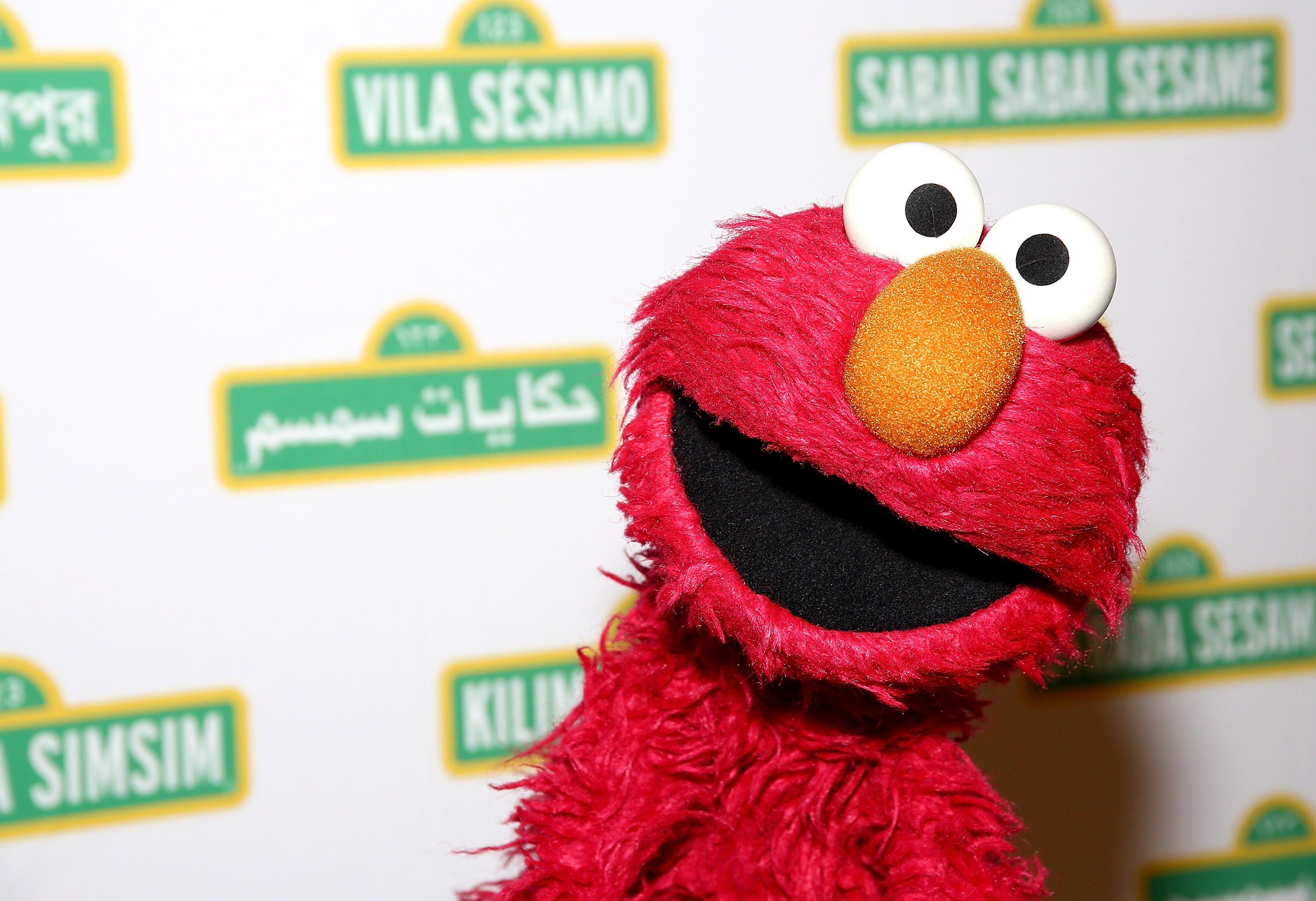 Elmo with 'Sesame Street' logos in the background