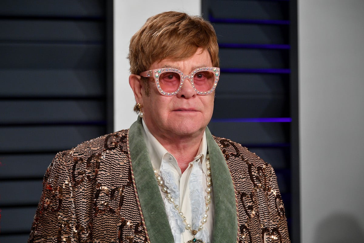 Elton John wearing sunglasses poses for photographers.
