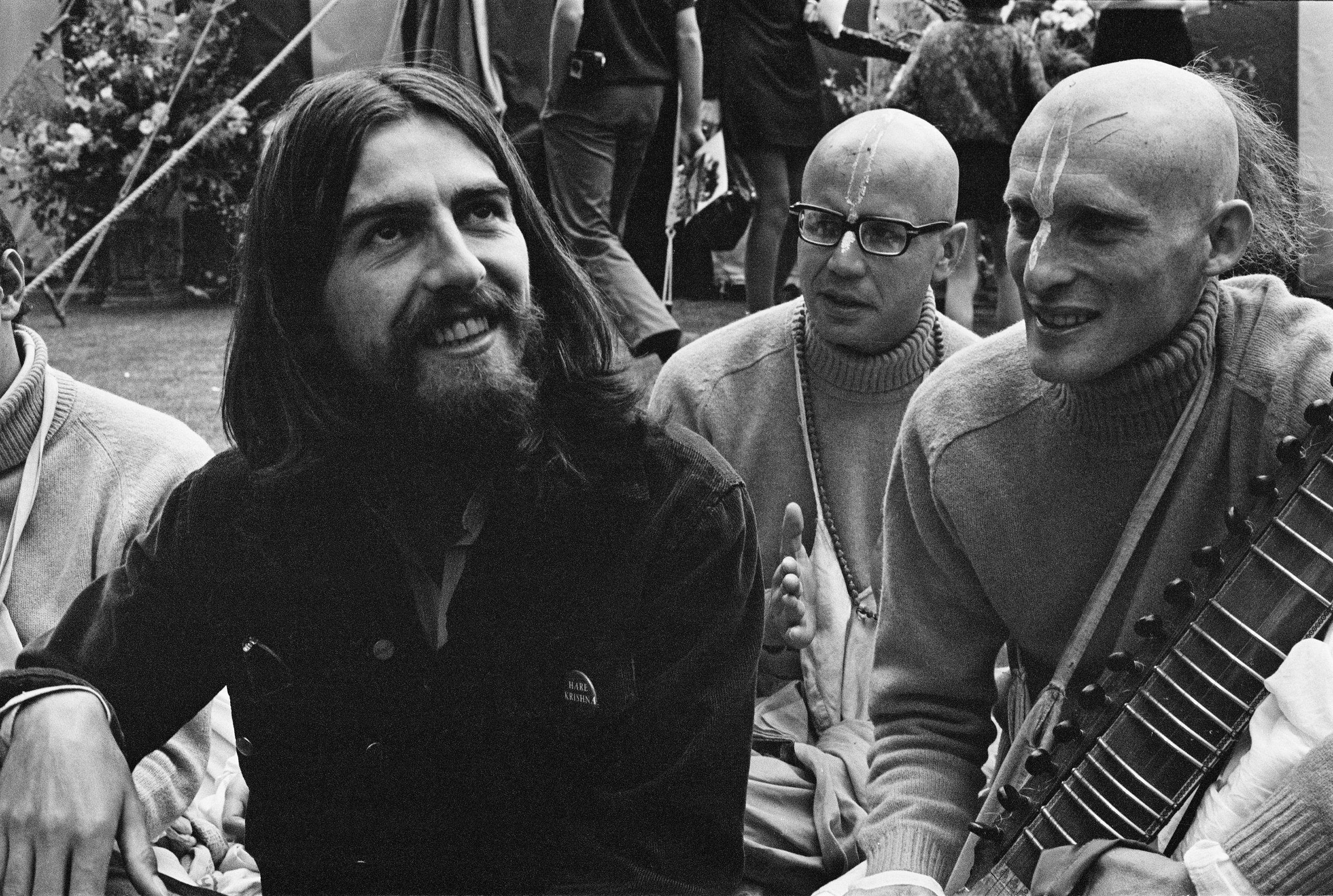 George Harrison sitting with two Hare Krishnas