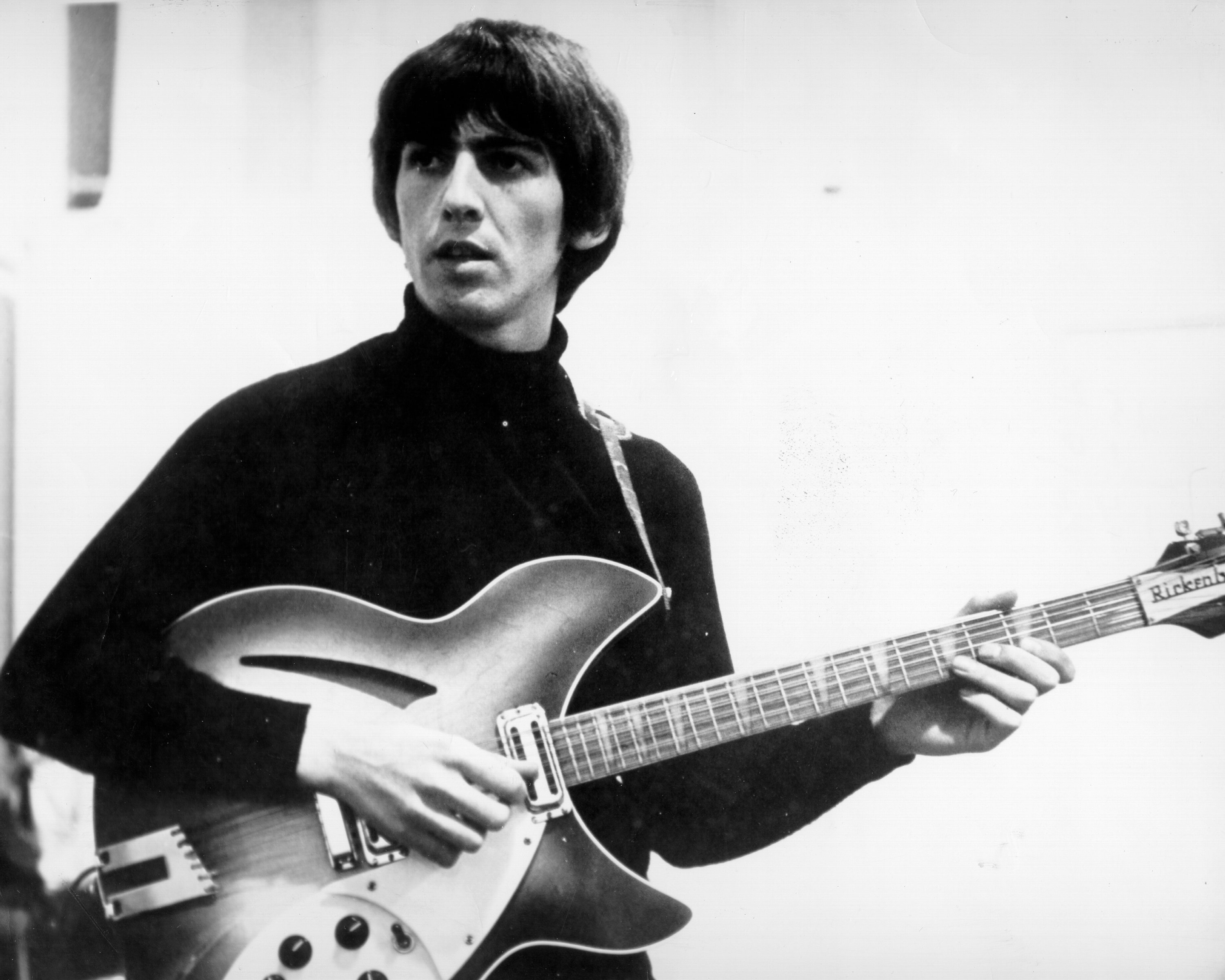 The Beatles' George Harrison playing songs on a guitar