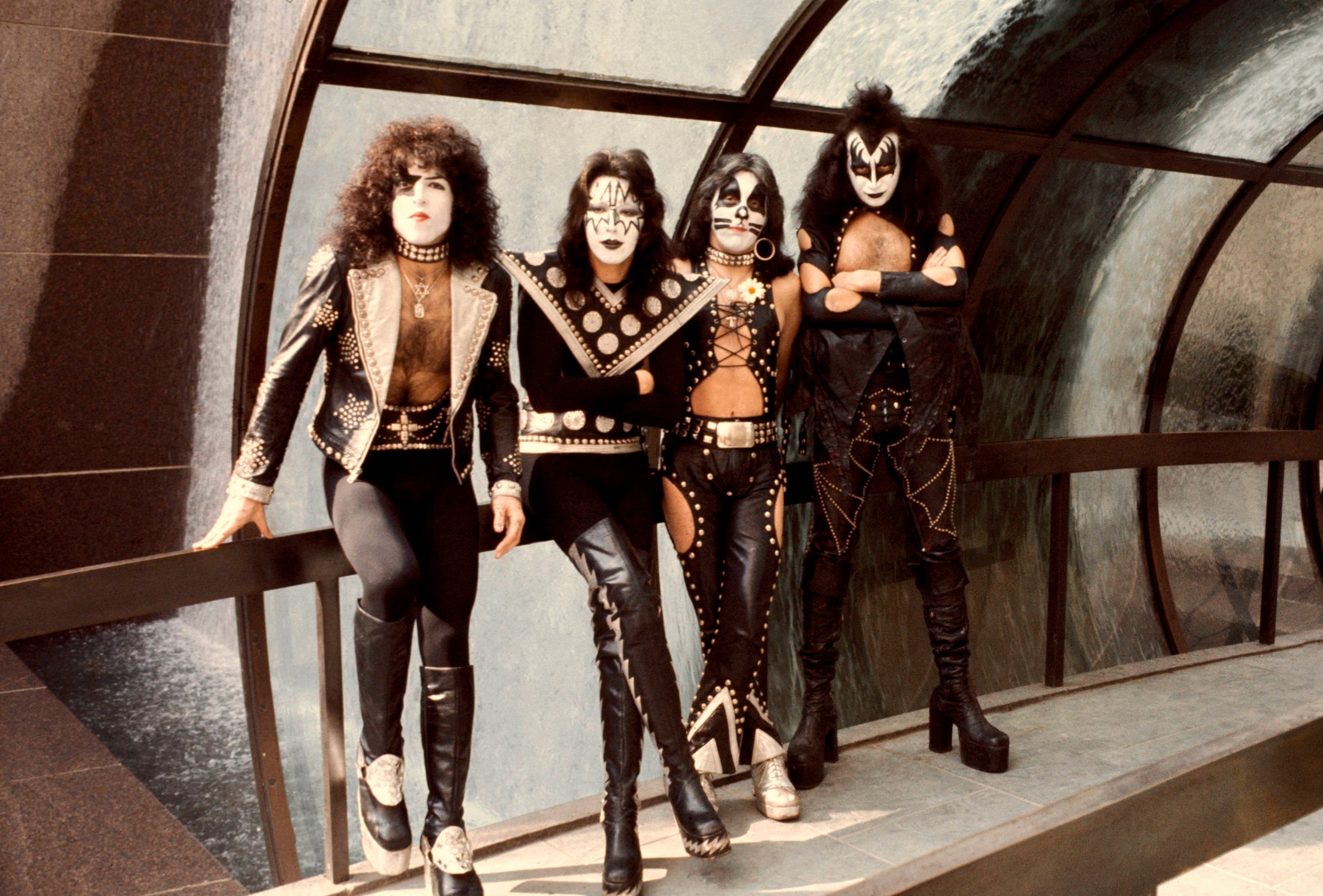 Kiss members Paul Stanley, Ace Frehley, Peter Criss, and Gene Simmons leaning on a railing