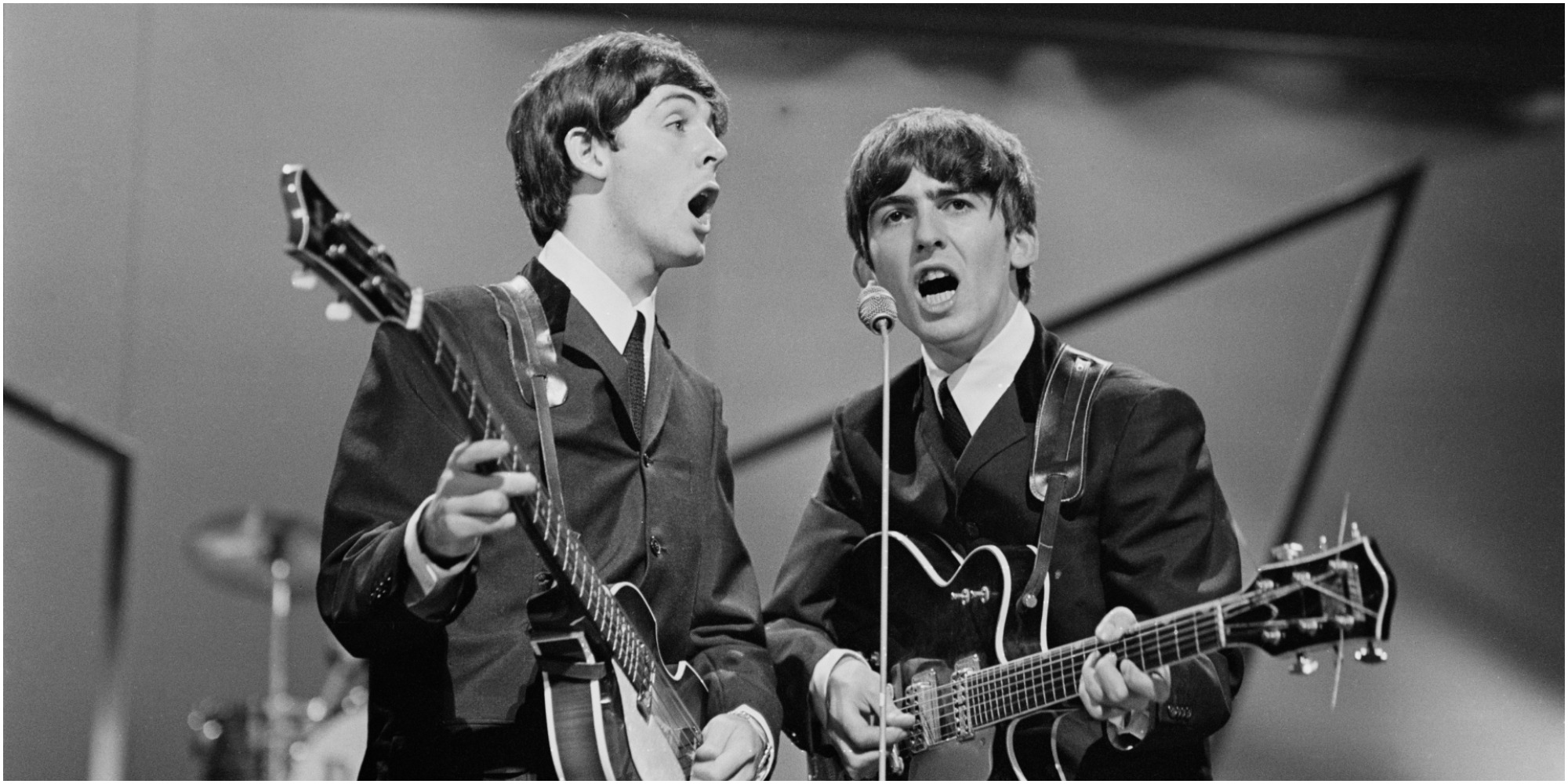 Paul McCartney and George Harrison perform on stage in 1963.