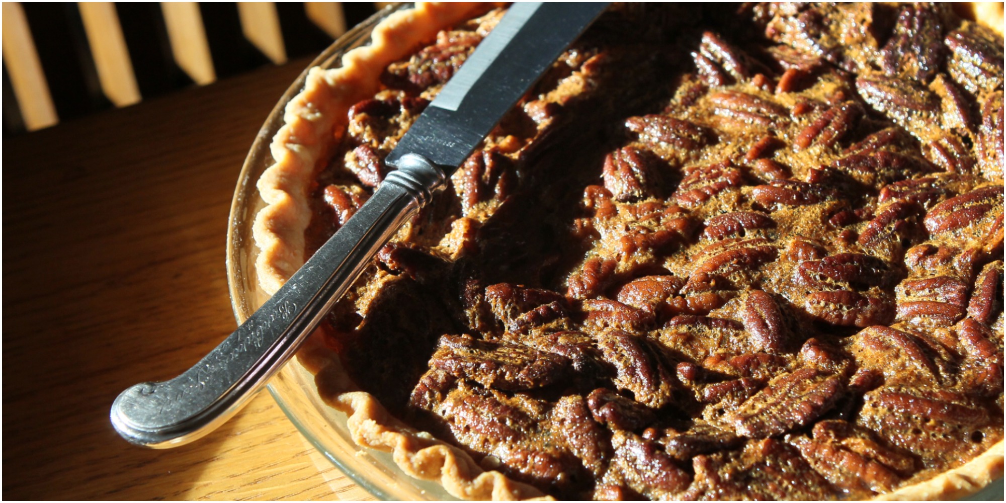 A photograph of a pecan pie with a knife lying across it.