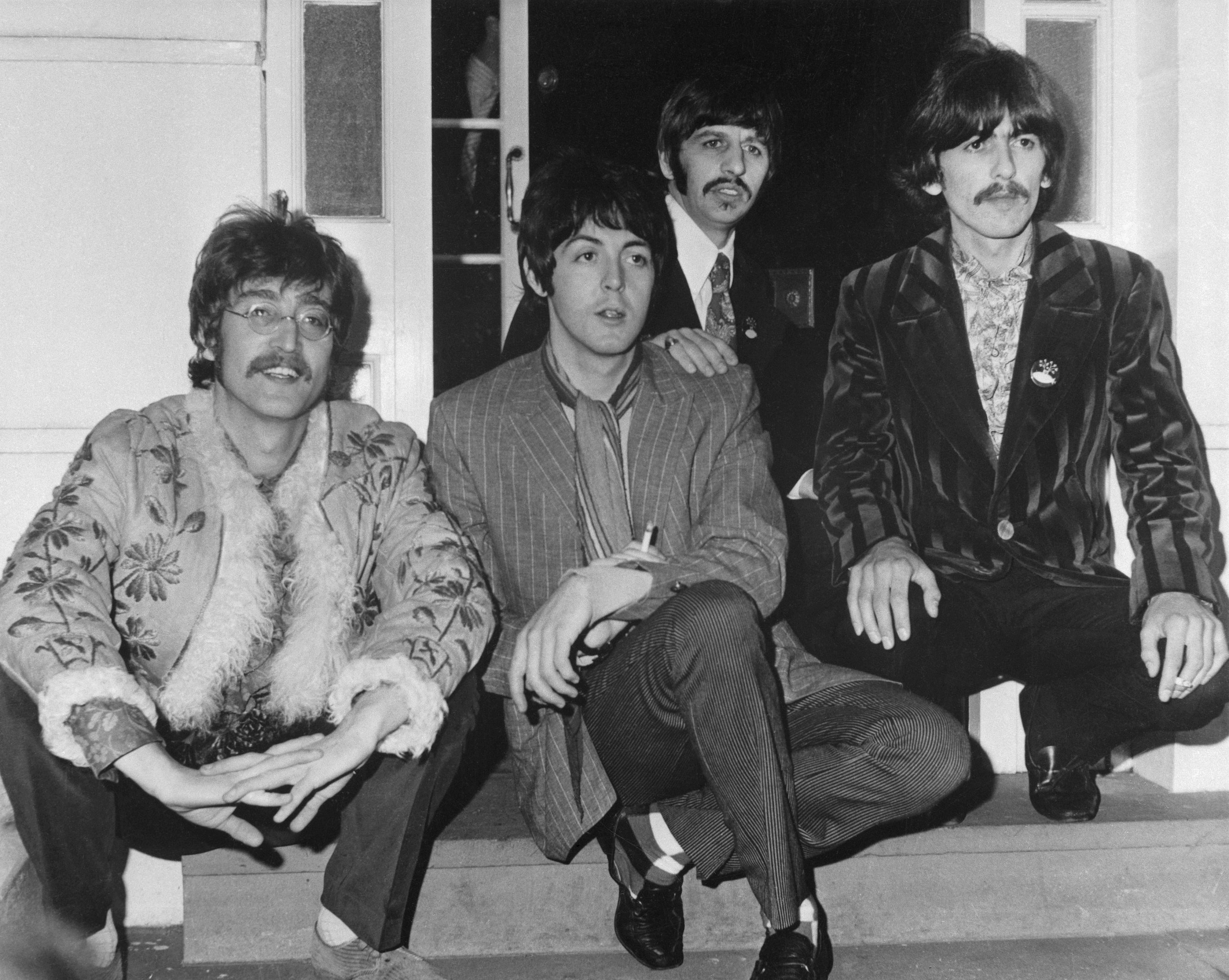 John Lennon, Paul McCartney, Ringo Starr, and George Harrison sitting on a step the year before The Beatles released the 'White Album'