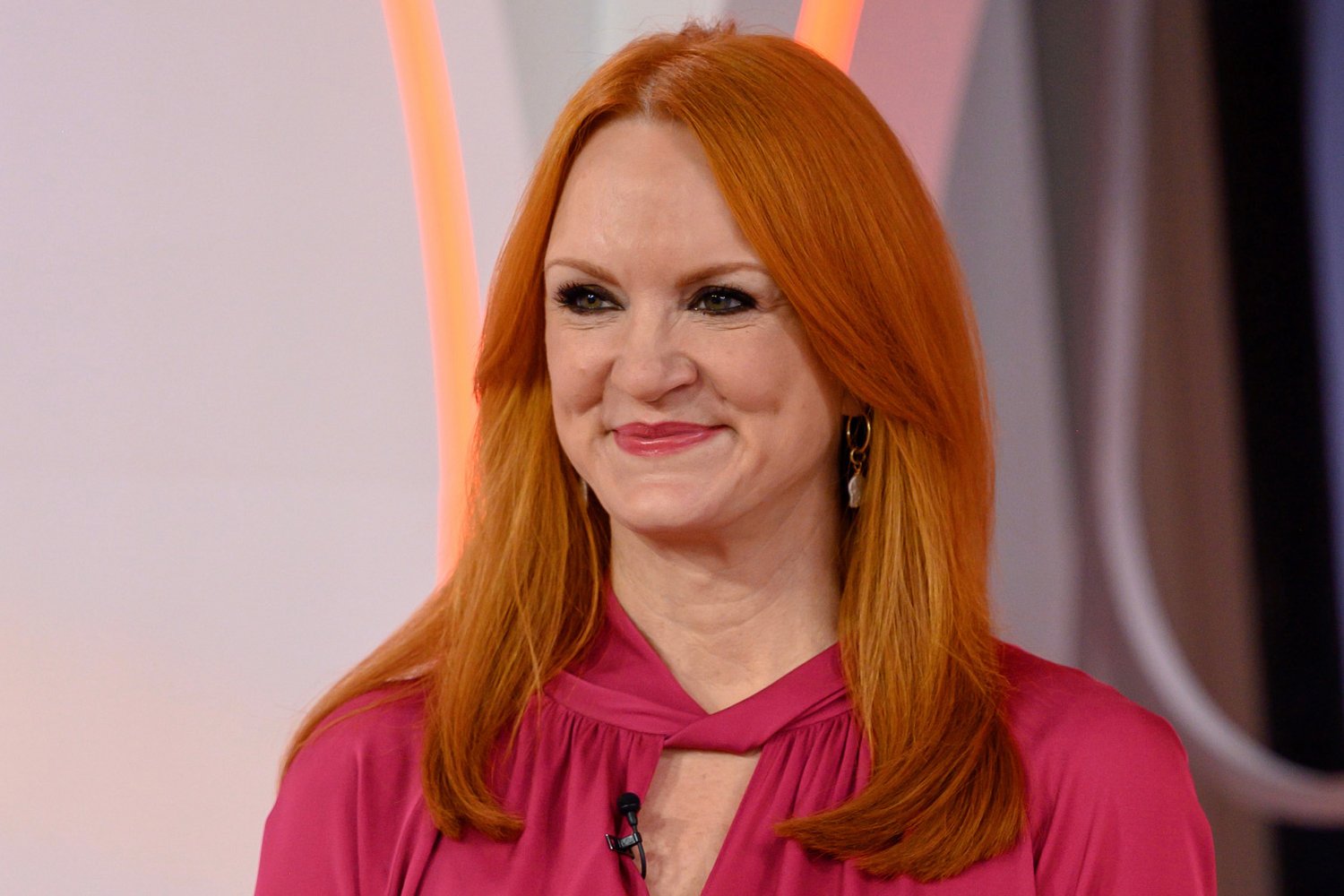 Ree Drummond smiles as she looks on wearing a pink blouse