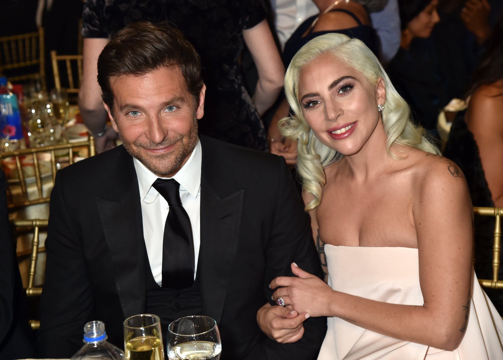 'A Star Is Born' actors Bradley Cooper and Lady Gaga smiling at their table at the Critics' Choice Awards