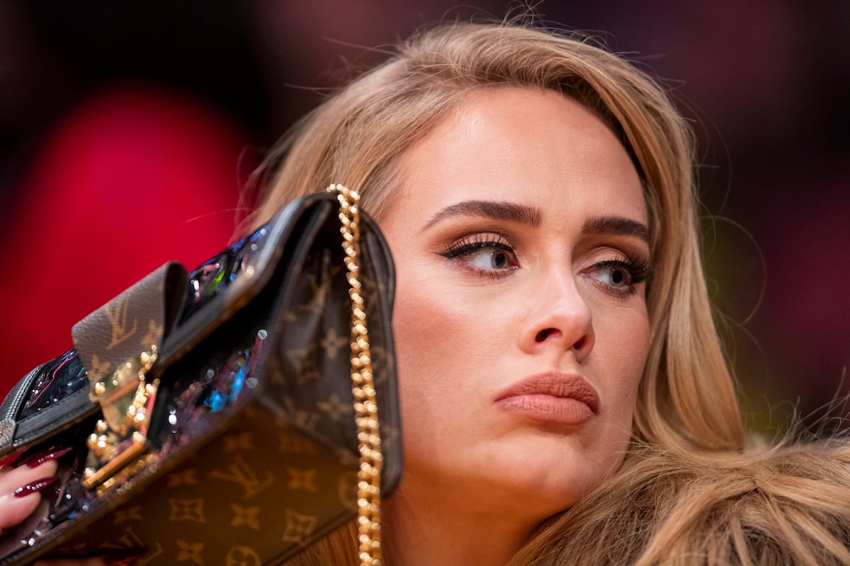 Singer Adele uses her purse to hide from the TV camera at a Lakers game