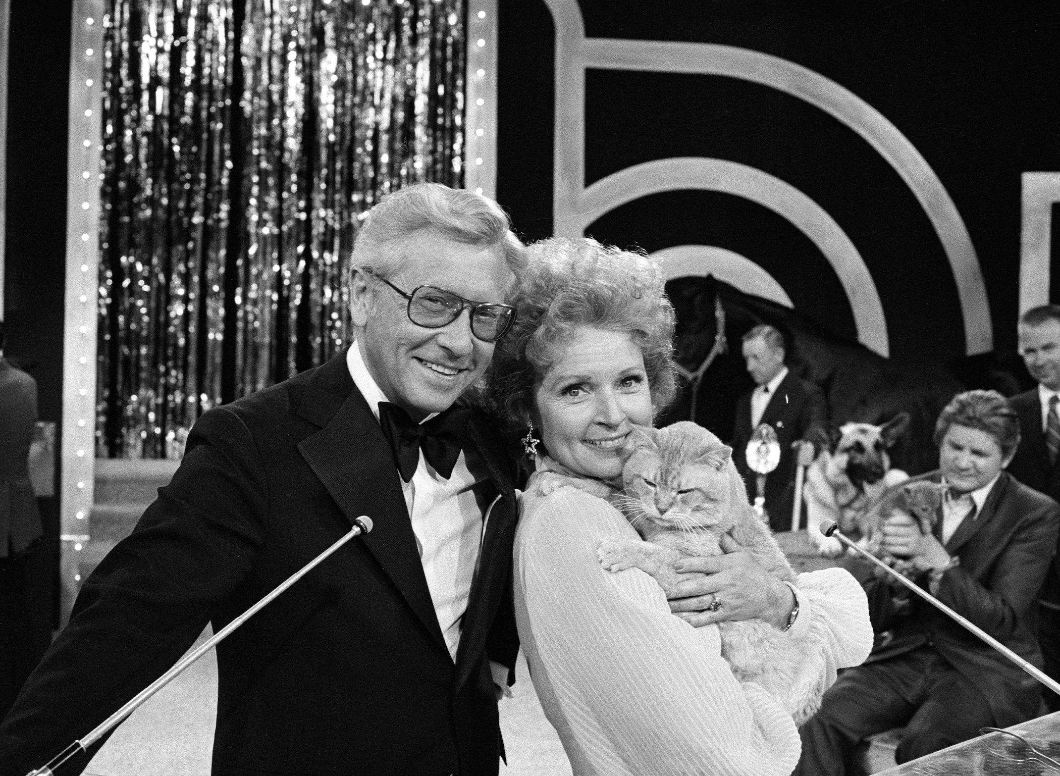 A black and white photo with Betty White's spouse Allen Ludden next to Betty White holding a cat and smiling