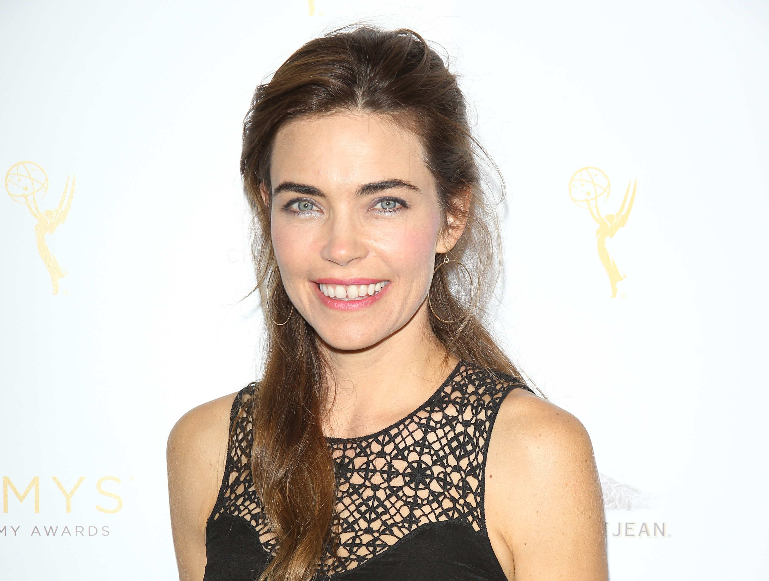 'The Young and the Restless' actor Amelia Heinle wearing a black dress and posing on the red carpet.
