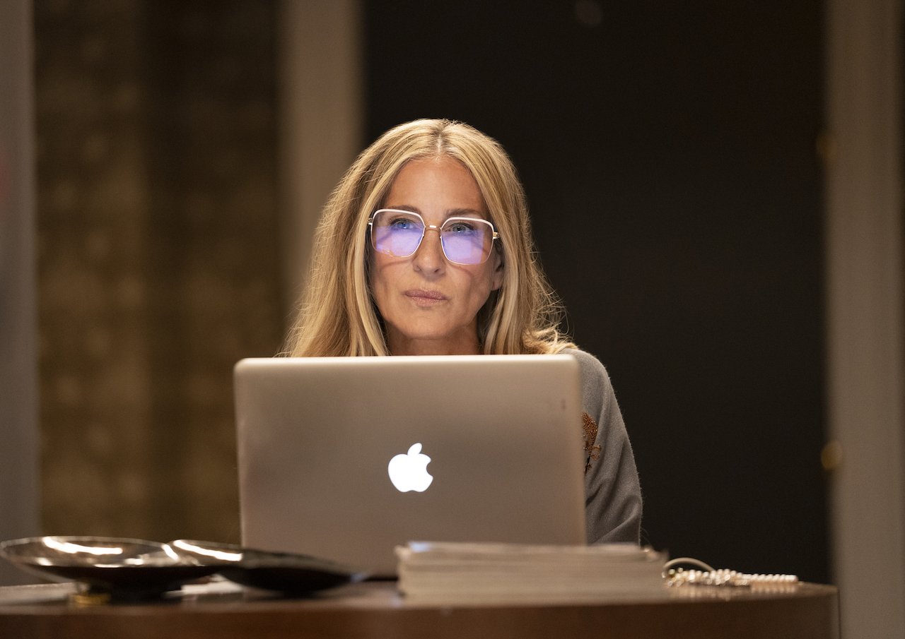 Sarah Jessica Parker as her 'Sex and the City' character Carrie Bradshaw in 'And Just Like That...' sits at a Mac computer wearing glasses. 'And Just Like That...' season 2 has not gotten ann official release date, but production has begun