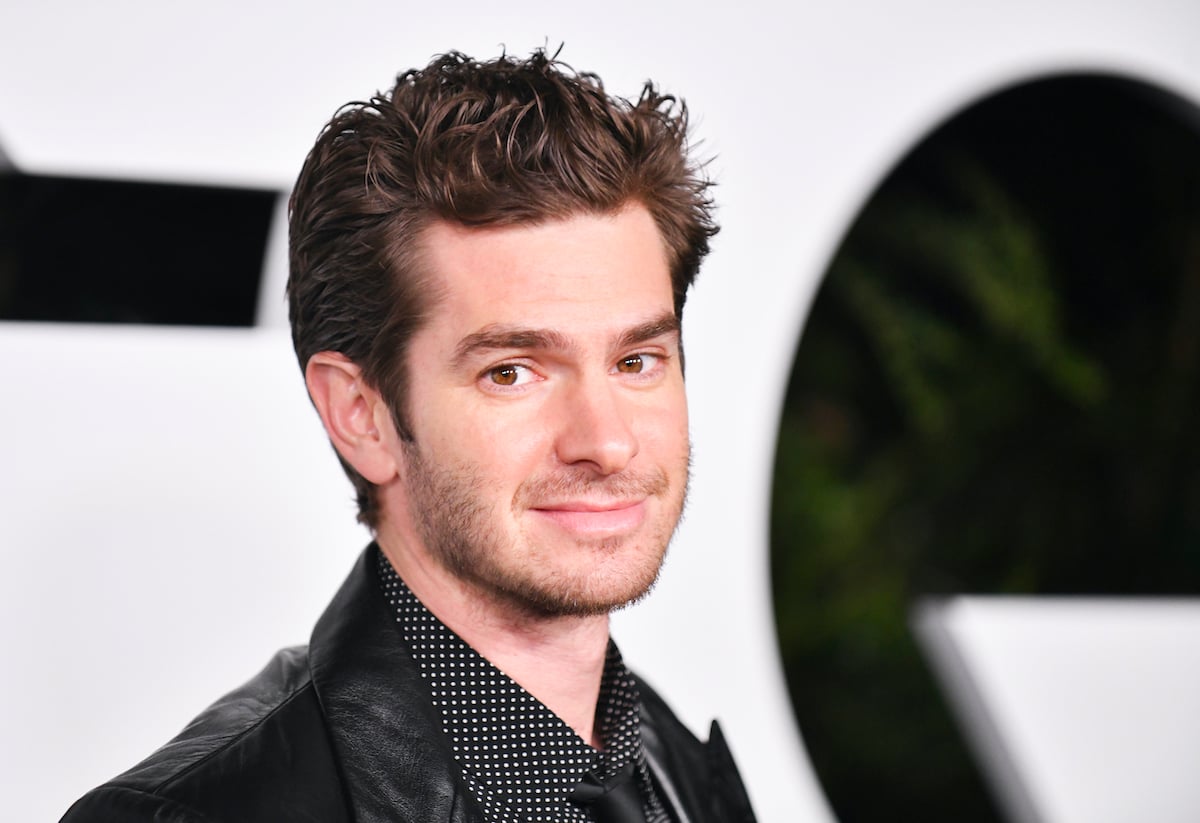 Andrew Garfield smiling in front of a white background
