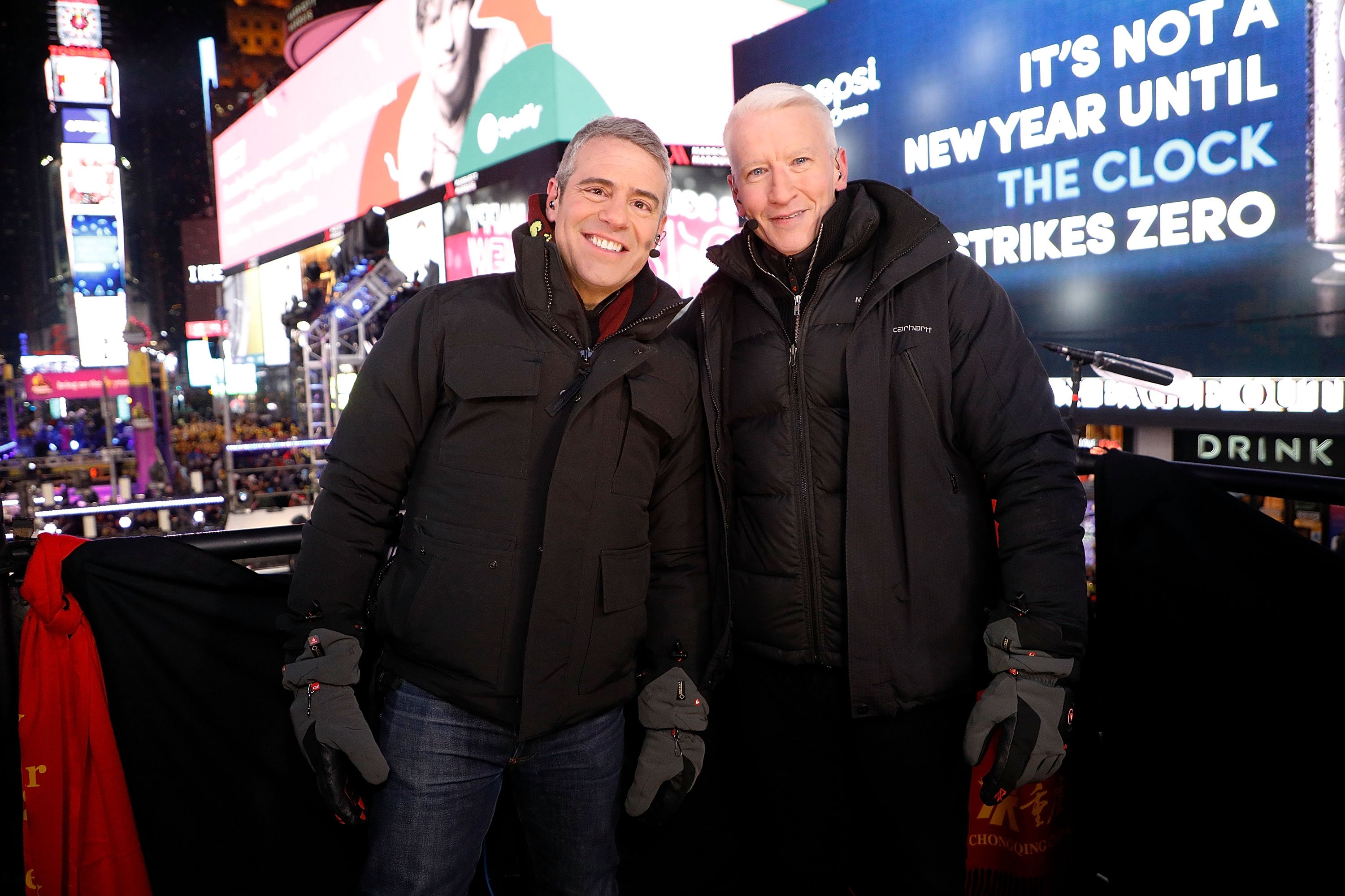 Andy Cohen and Anderson Cooper, both wearing winter coats, in Times Square on New Year's Eve