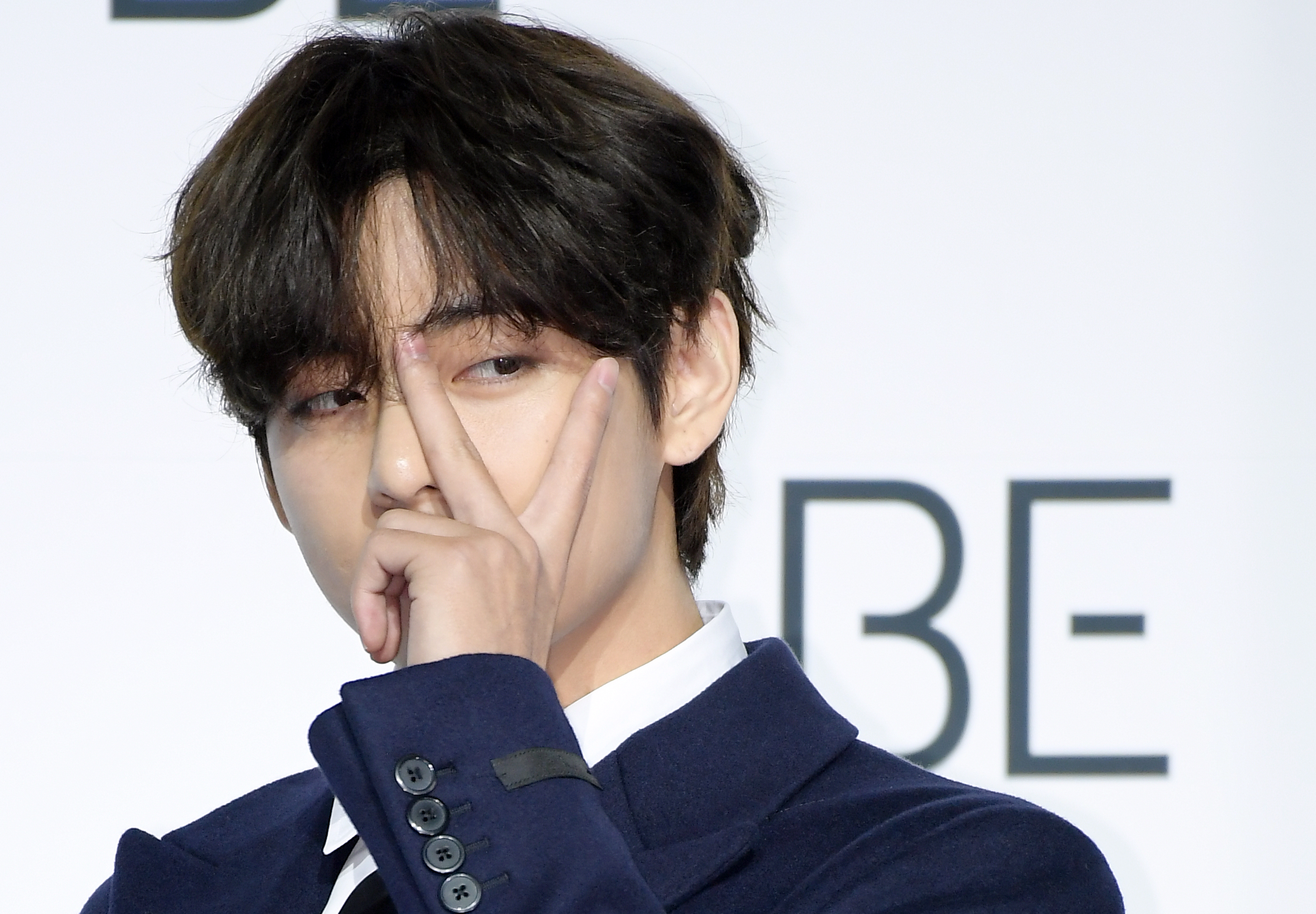 V of BTS holds up the peace sign during the band's press conference for 'BE"