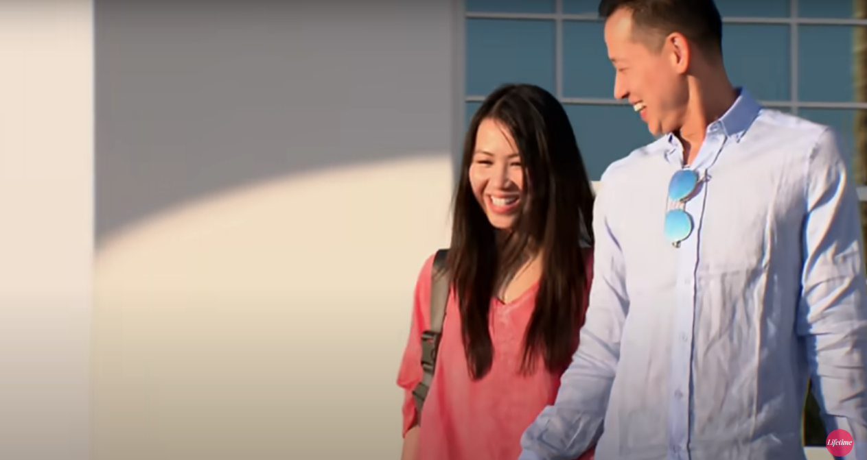 Bao, in a pink shirt, and Johnny, in a light blue button down, smiling and walking on 'Married at First Sight' Season 13