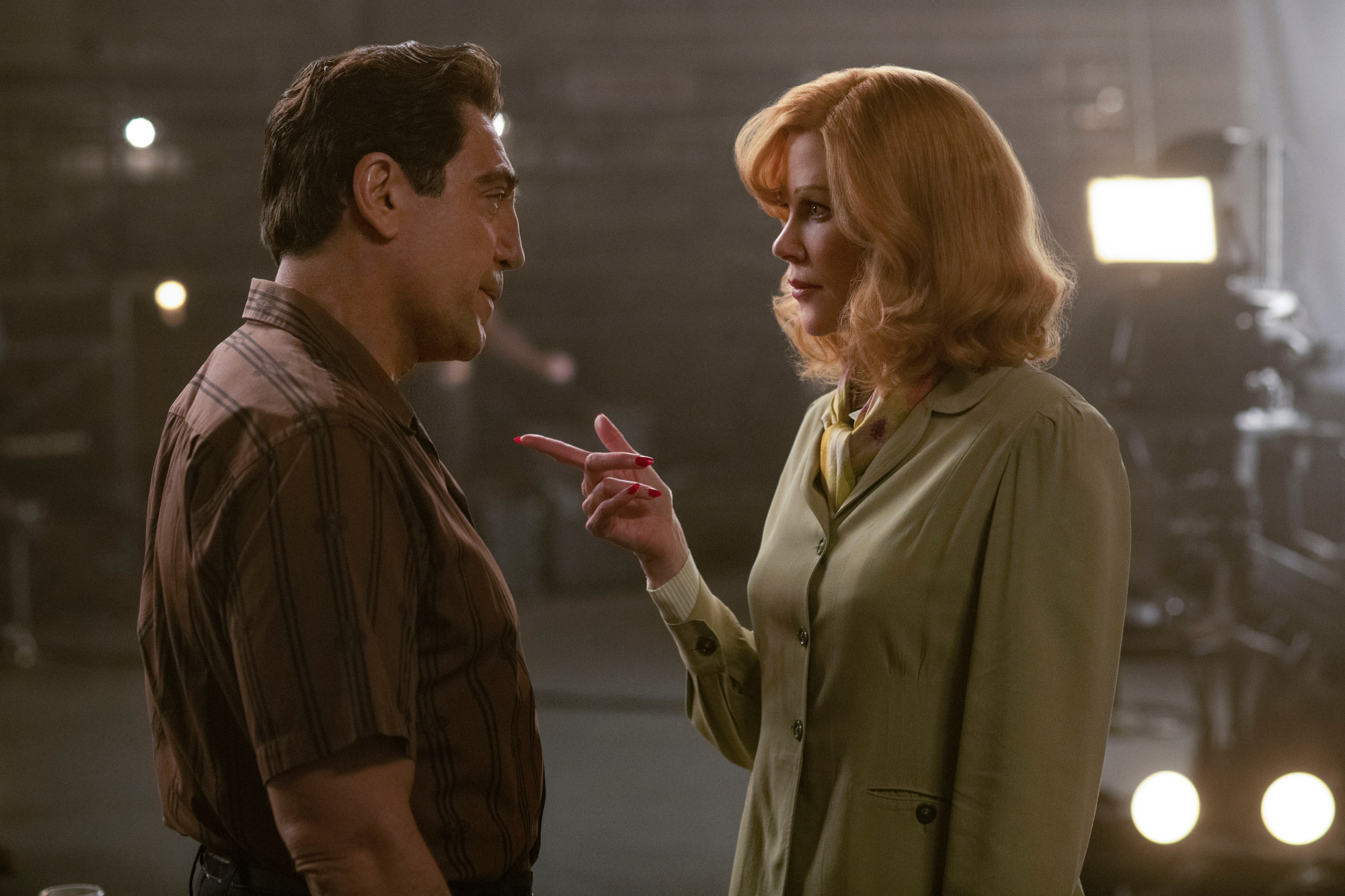 'Being the Ricardos' review Javier Bardem as Desi Arnaz and Nicole Kidman as Lucille Ball standing across from each other with a light behind them