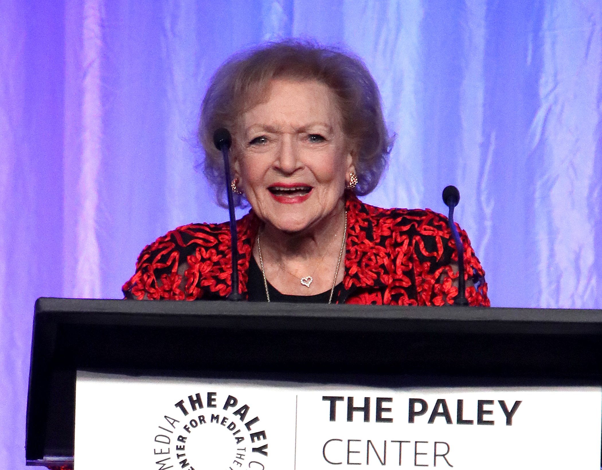Betty White speaking at the Paley Honors in Hollywood against a purple background
