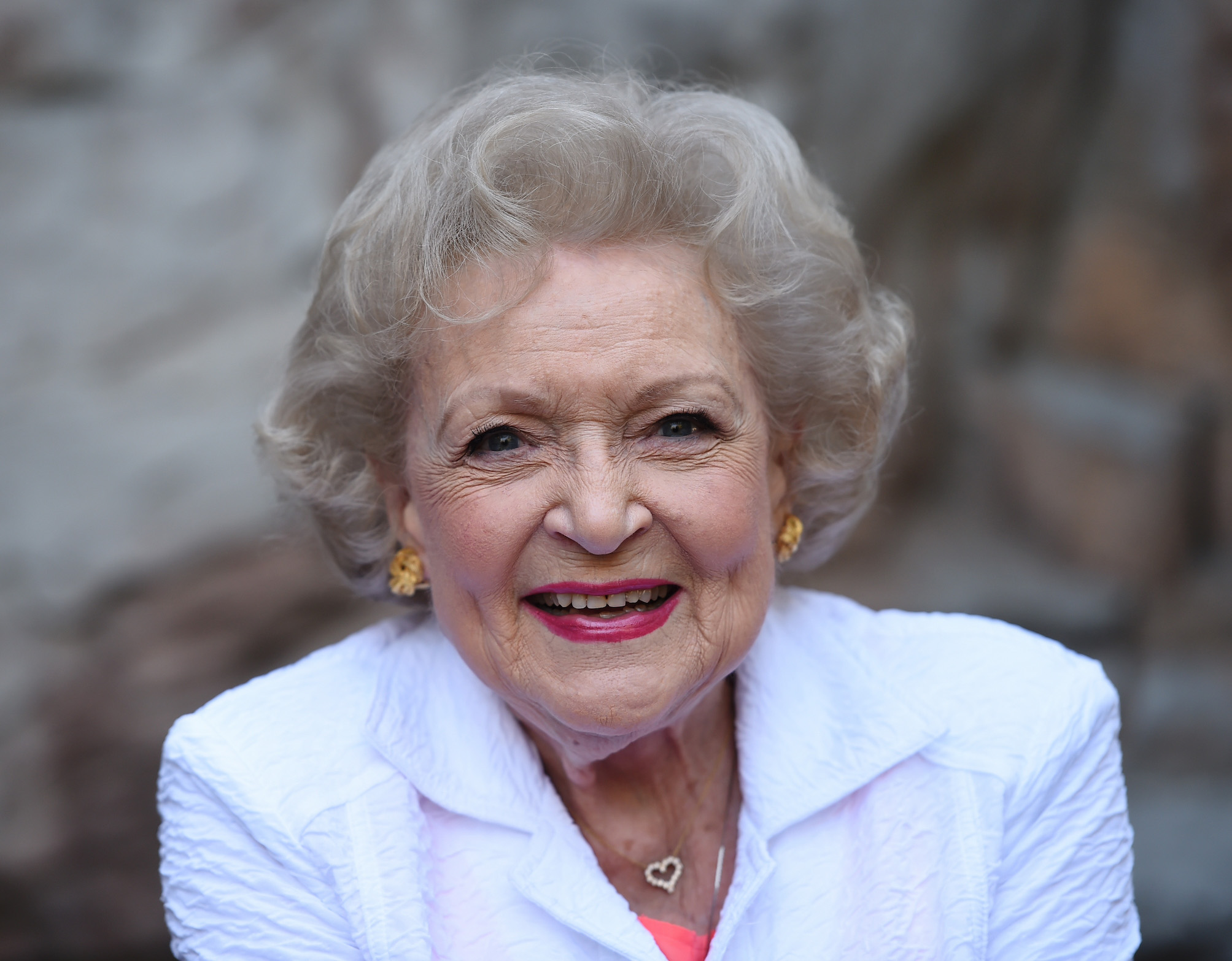 A head shot of Betty White smiling and wearing white