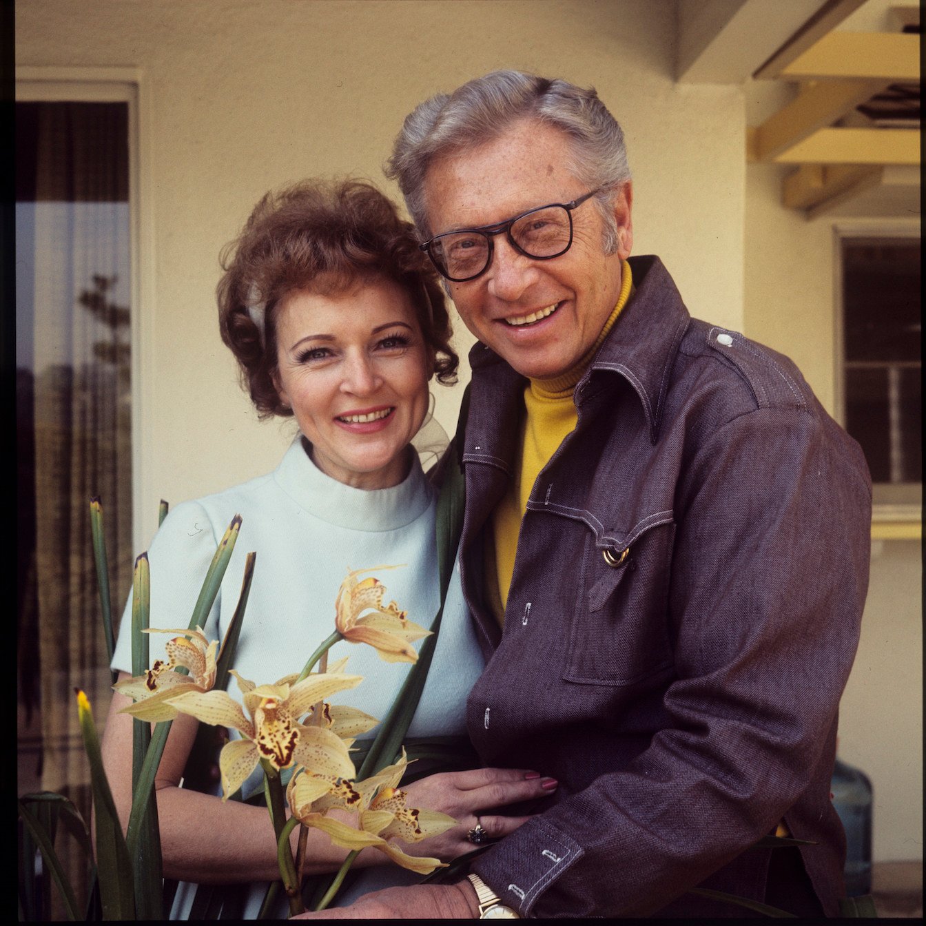 Betty White and Allen Ludden smiling and embracing each other outside. Betty White's stepchildren were Allen Ludden's three kids