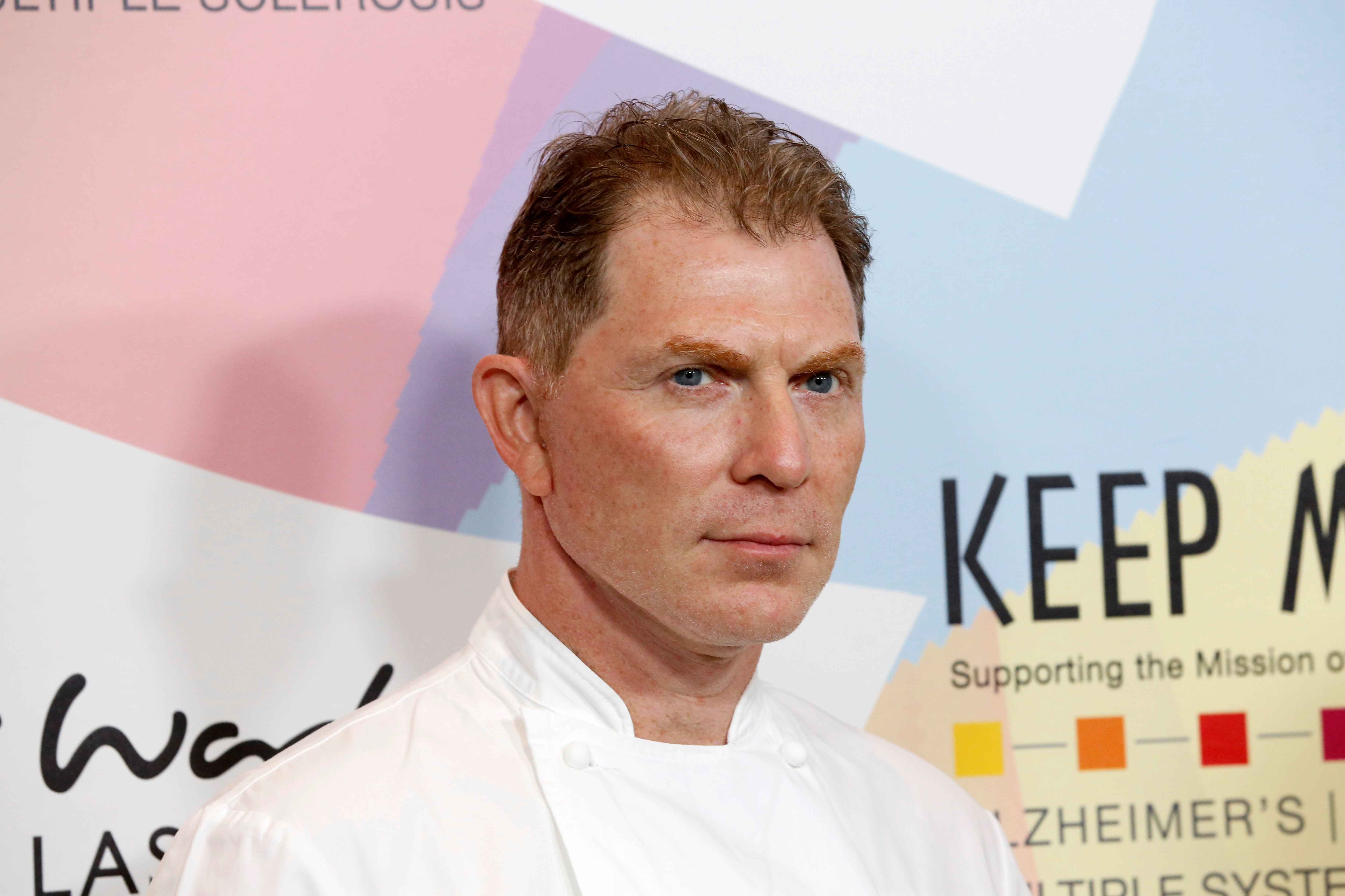 Food Network star Bobby Flay, who has a superb chocolate chip cookie recipe, in a chef's coat standing against a colorful background