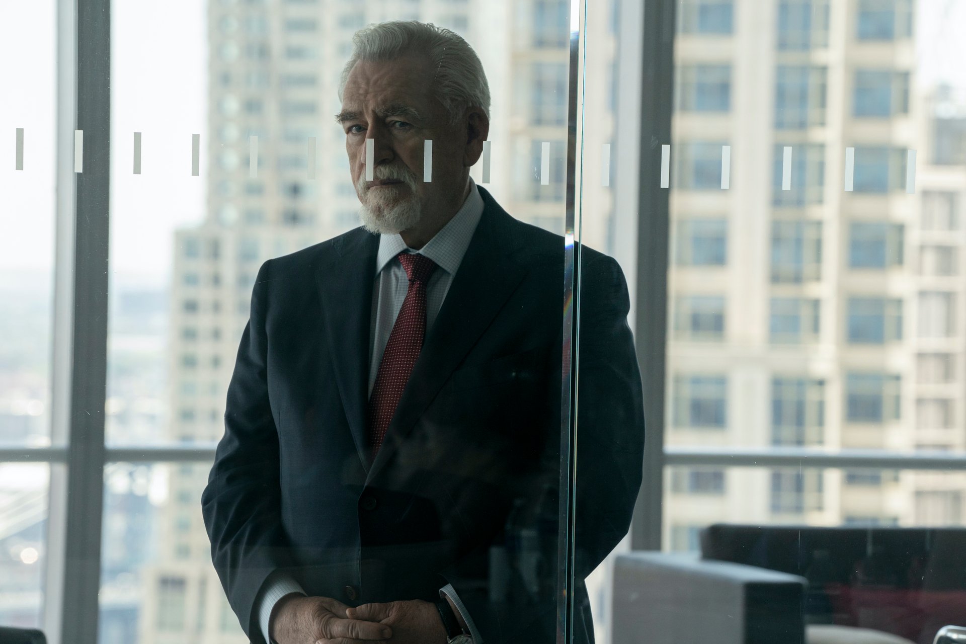 Brian Cox as Logan Roy in 'Succession' Season 3 Episode 8. He's standing behind glass doors and looking out.