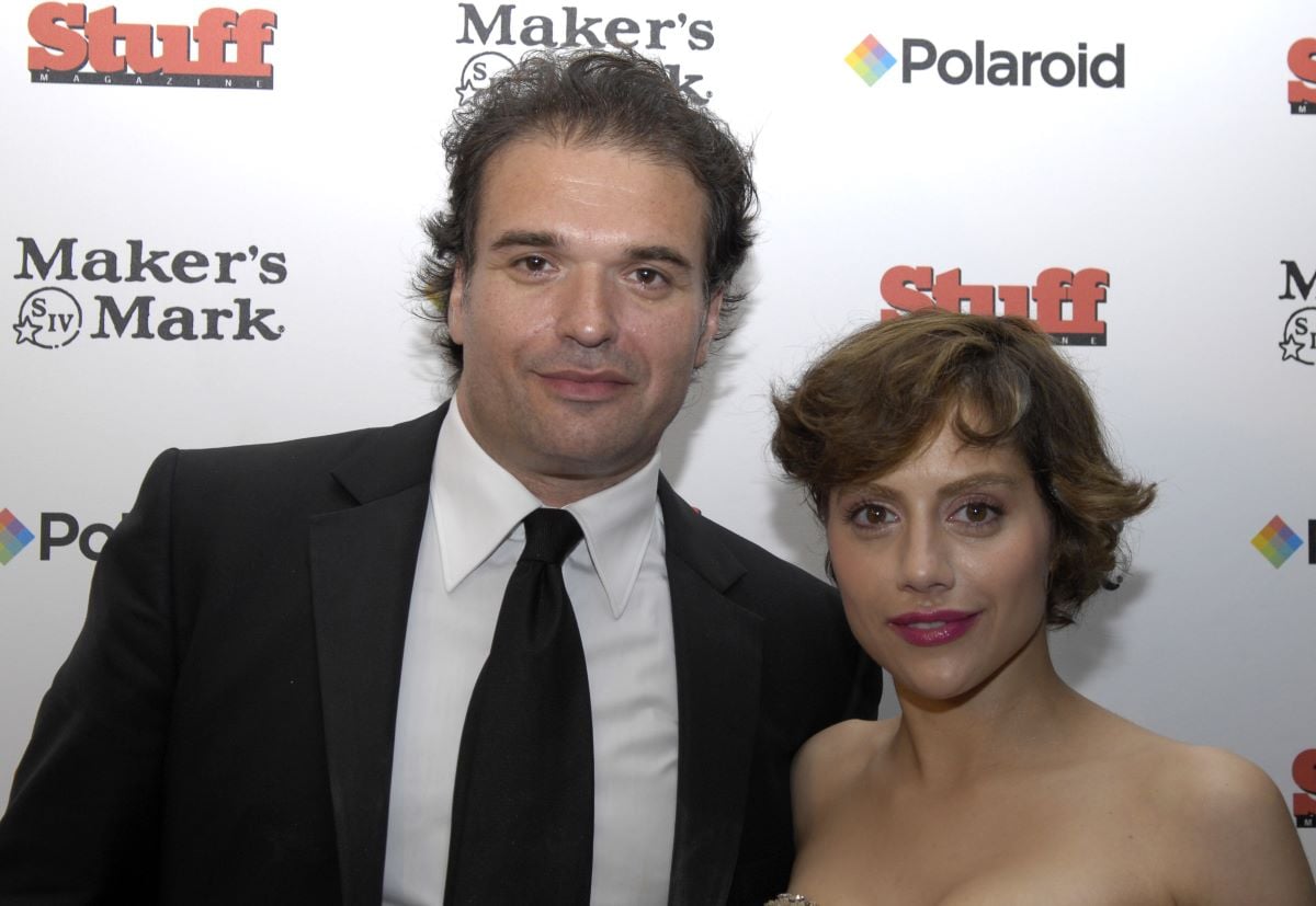 Simon Monjack in a black suit and tie, standing next to Brittany Murphy