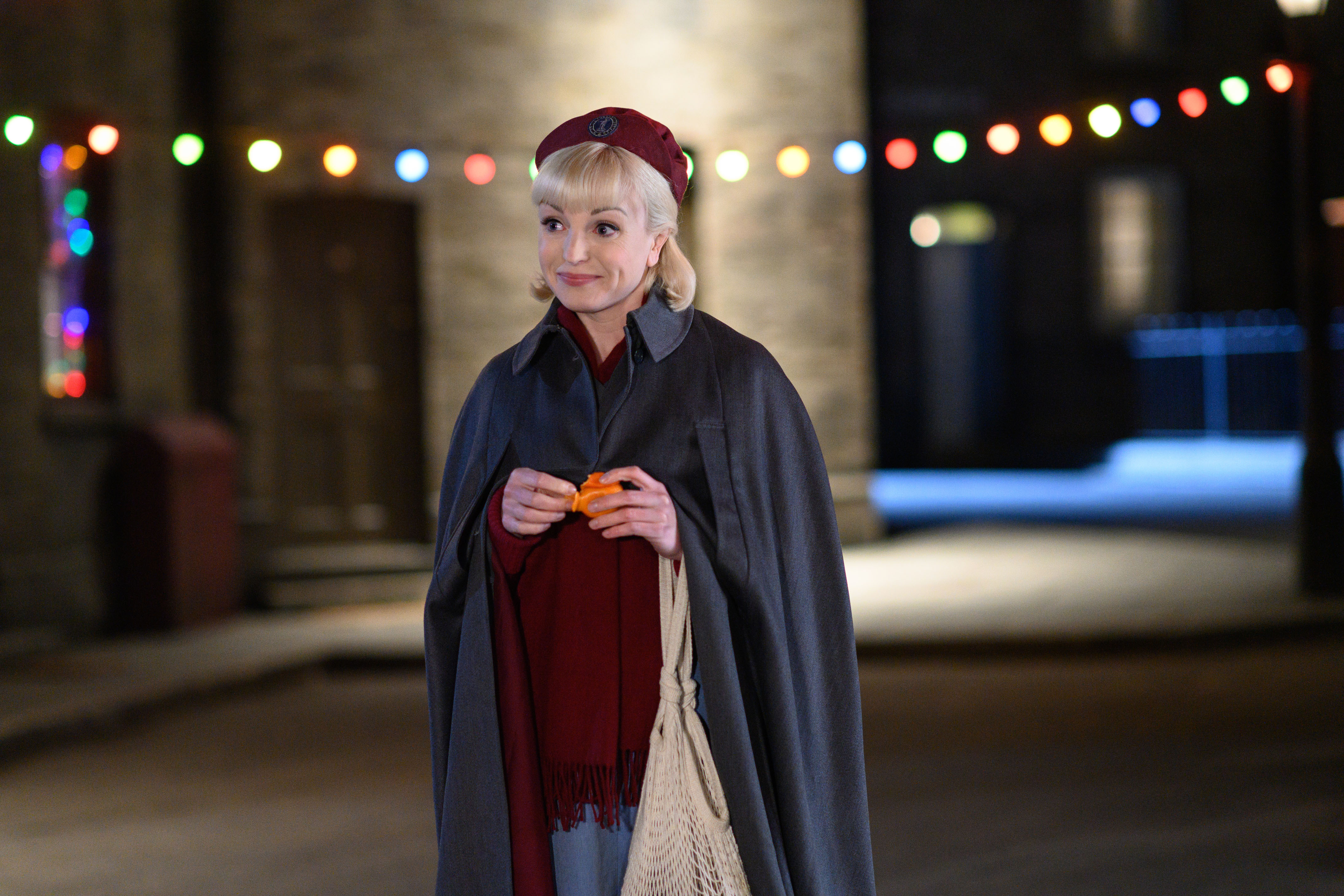 Helen George as Trixie, wearing a cape and standing in the street, in the 2021 'Call the Midwife' Christmas special