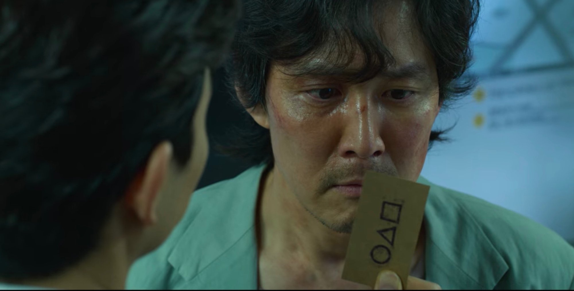 Character Seong Gi-hun for 'Squid Game' and 'Squid Game' Season 2 looking at calling card.